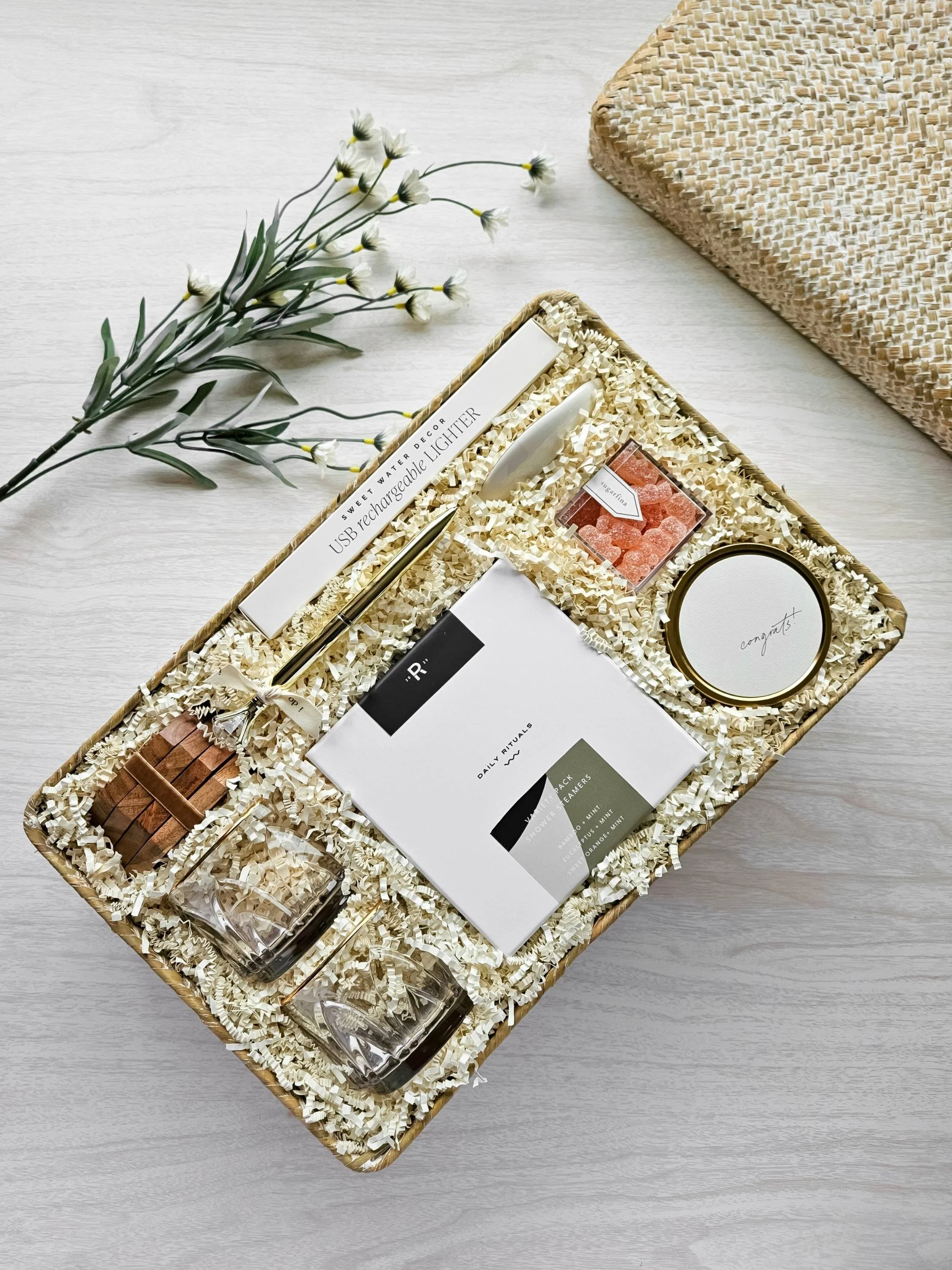 Full wedding gift basket view of The Vow with rose‑tinted glasses, shower steamers, champagne gummies, Mrs. ring dish, congrats candle, diamond ring pen, USB lighter, coasters, and more.