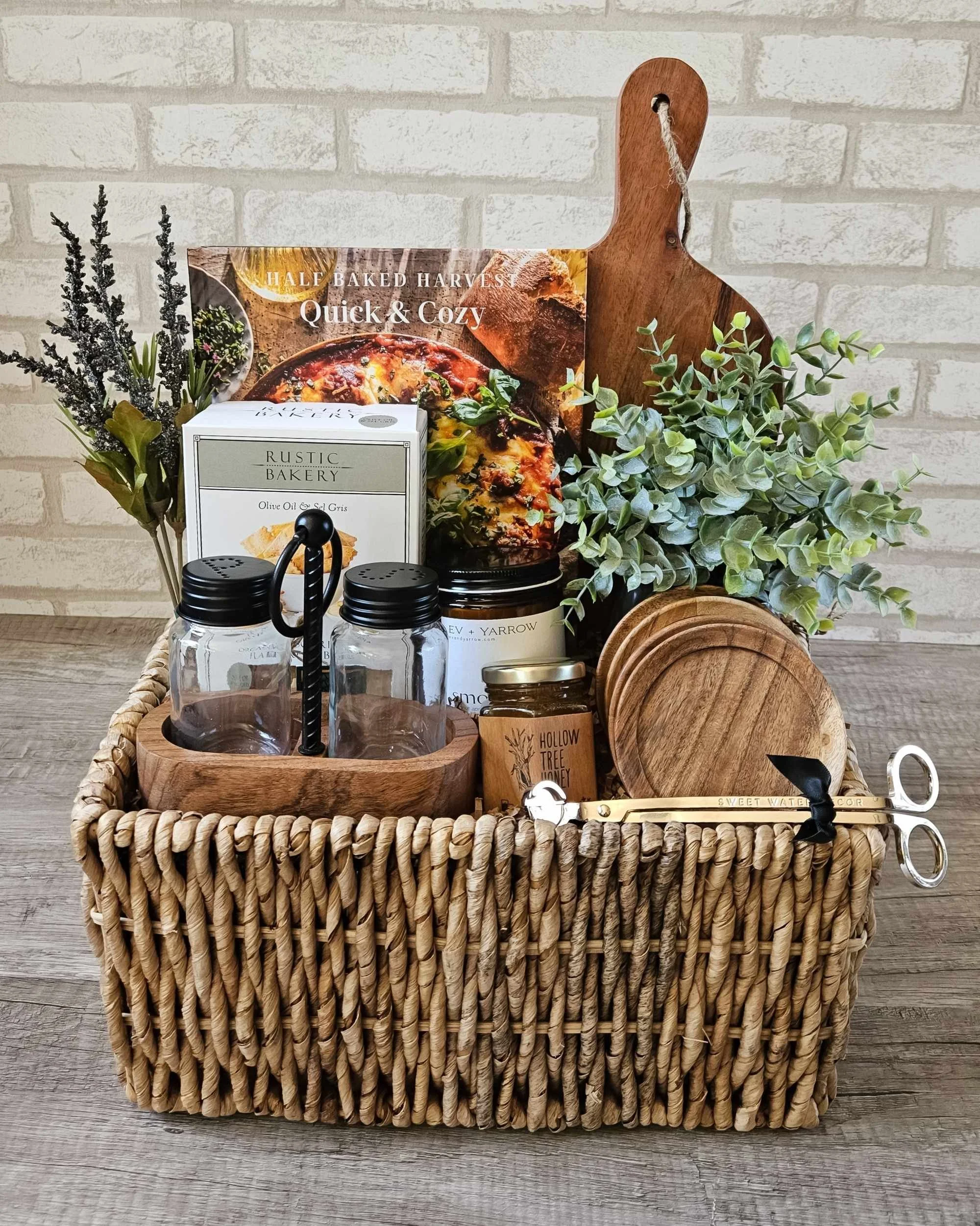 Cozy fall gift basket with cookbook, candle, and gourmet snacks for housewarming or client appreciation