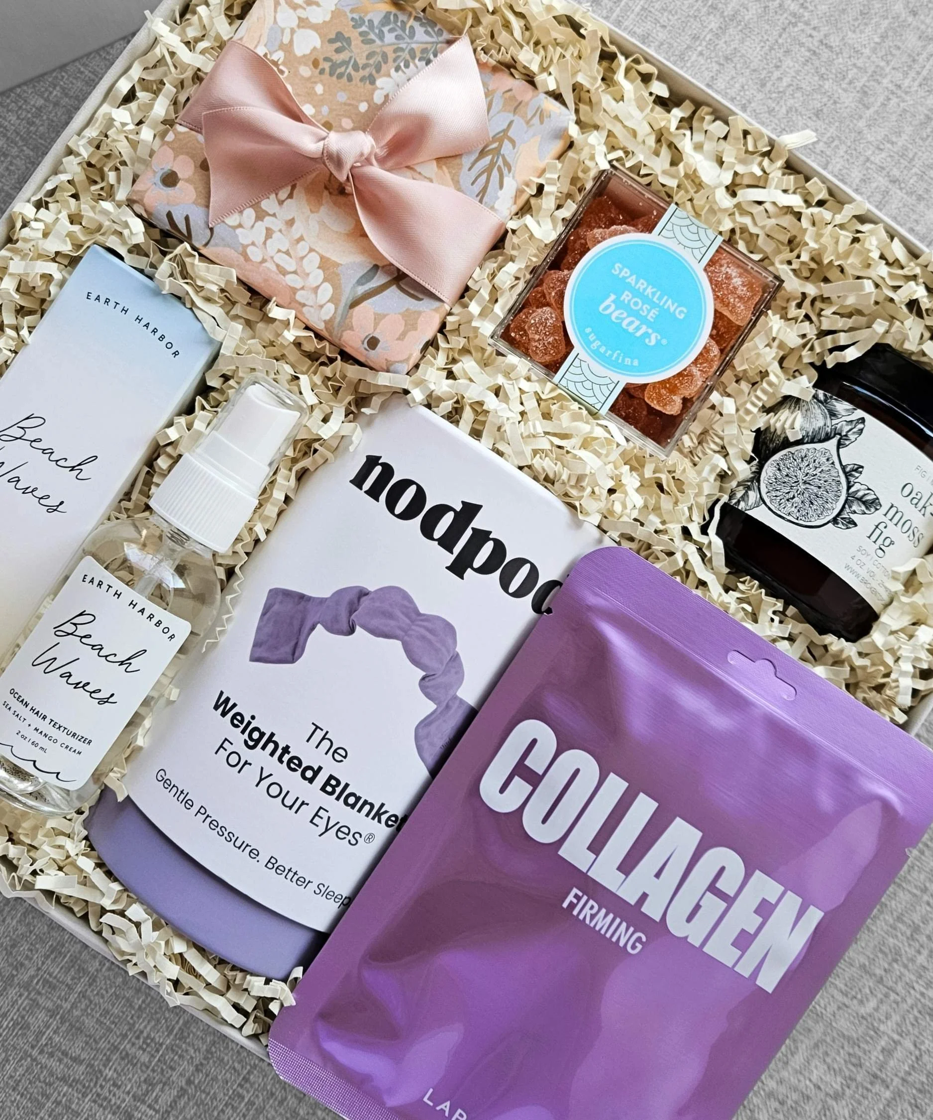 Luxury spa gift box with collagen sheet mask, oak moss candle, champagne gummies, beach wave spray, and rose eye gels.