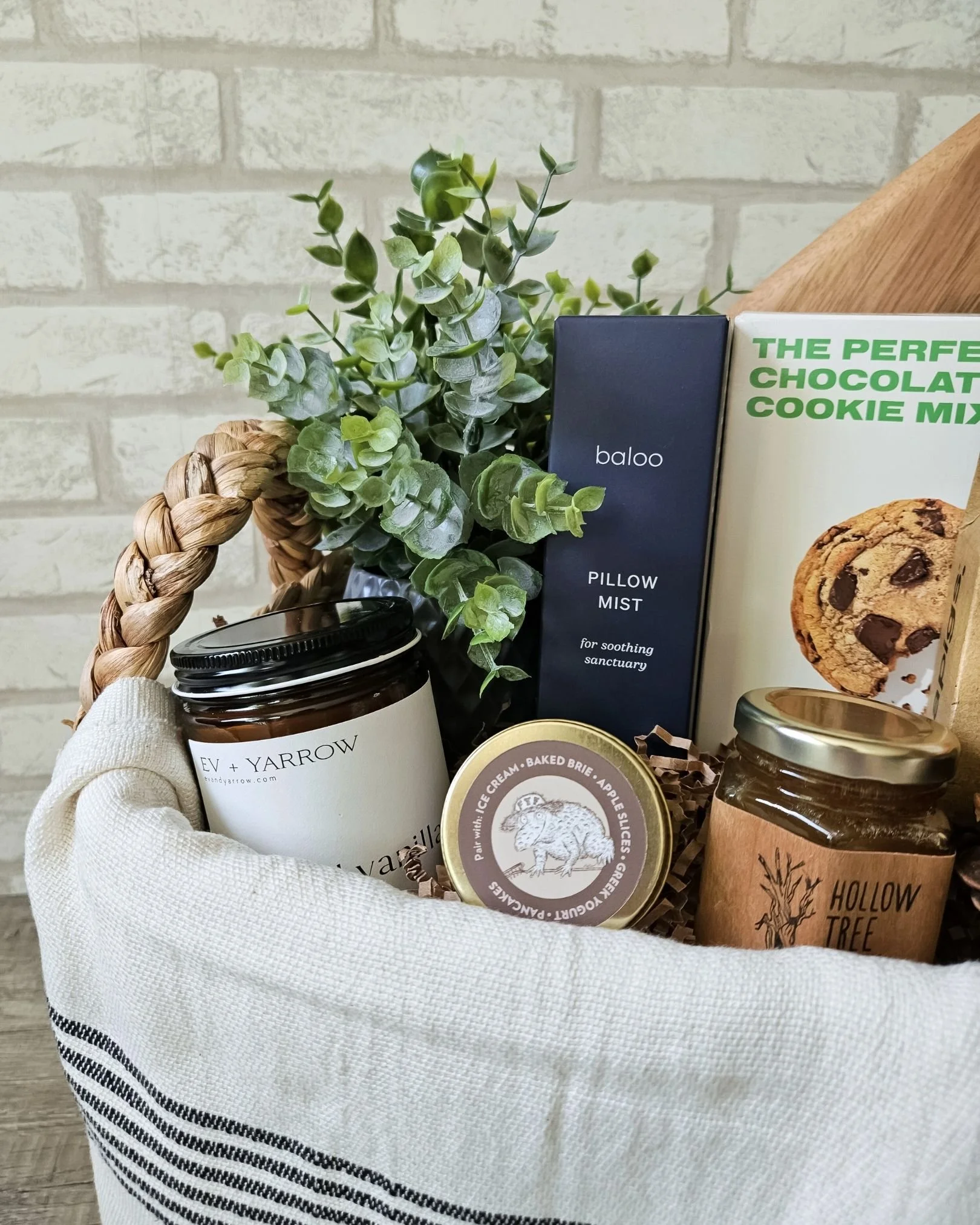 Cozy host gift basket with gourmet cookies, artisan tea, pillow mist, and wood serving board for holiday gifting.