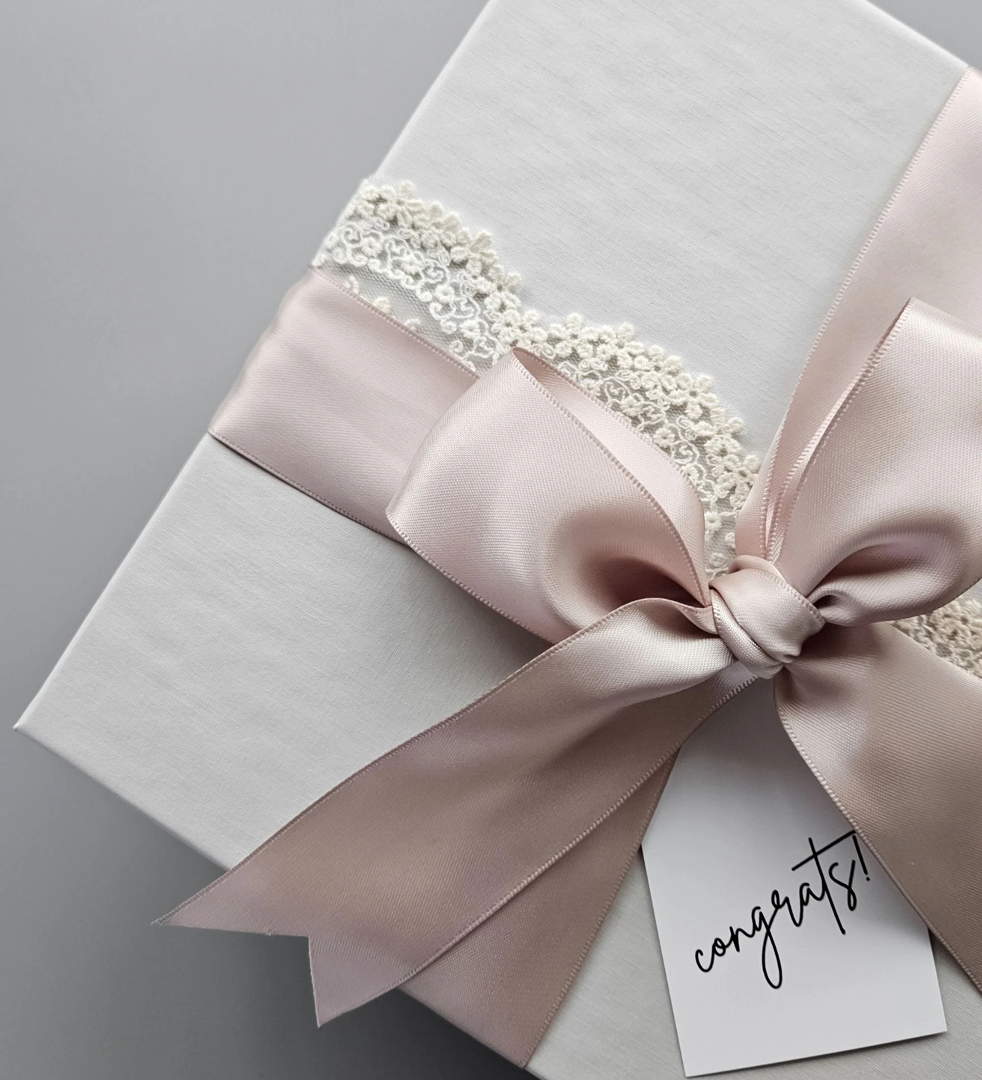 Close‑up of lace ribbon and double satin mauve ribbon tied around a light gray linen gift box for the Something Blue gift box