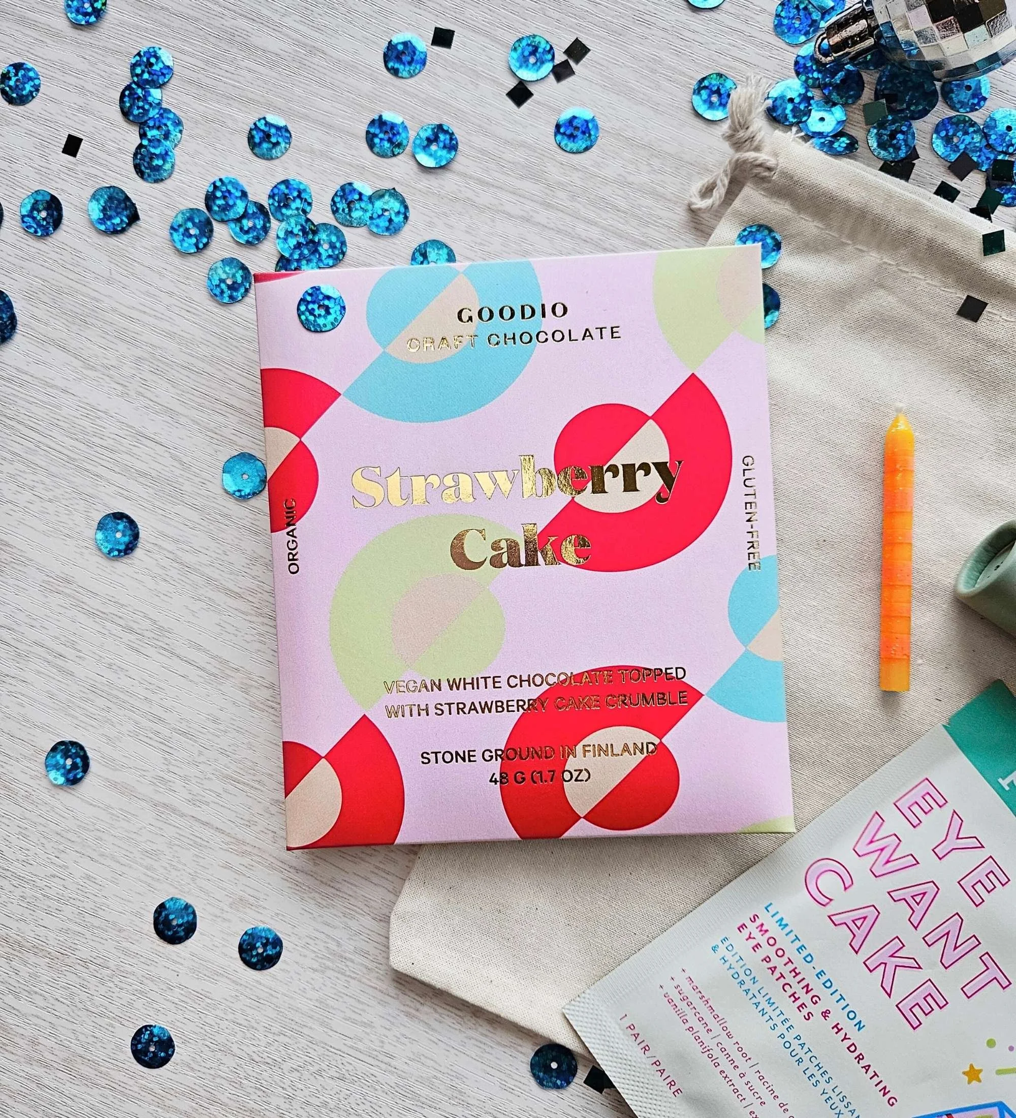 Budget‑friendly birthday gift with a strawberry cake chocolate bar, eye gels, lip balm, and a single birthday candle.