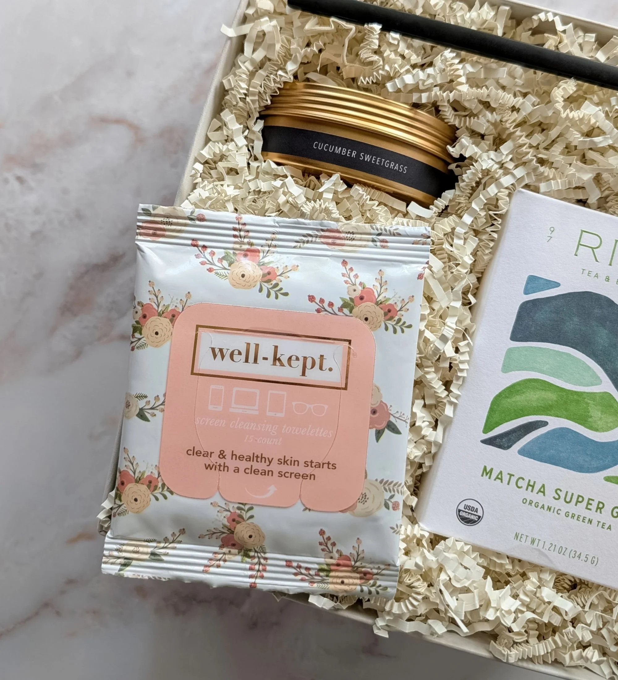 Refreshing gift box featuring matcha tea, floral wipes, a chic candle snuffer, and a cucumber sweet grass travel candle.