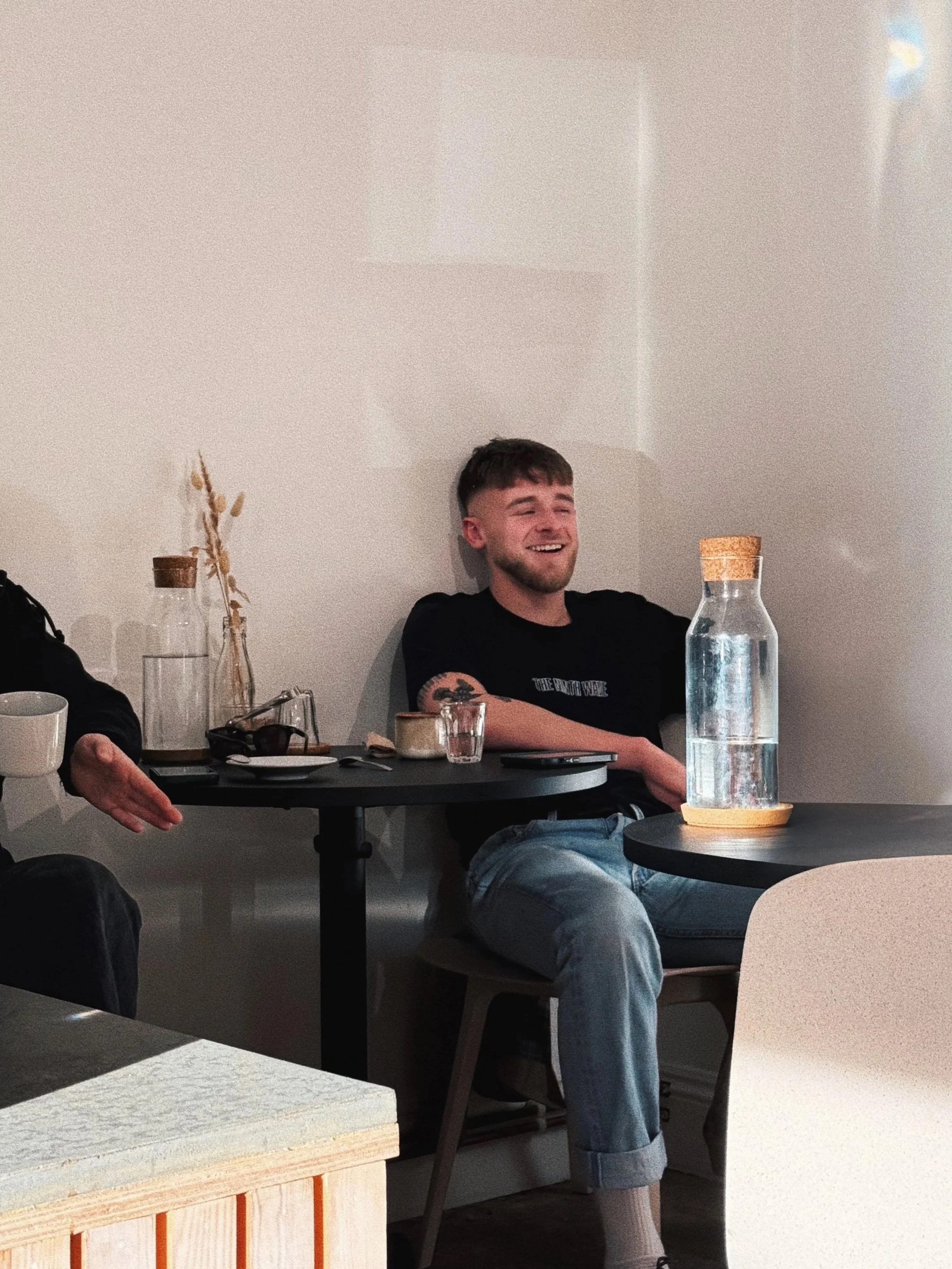 A young handsome chap laughing with friends enjoying his coffee