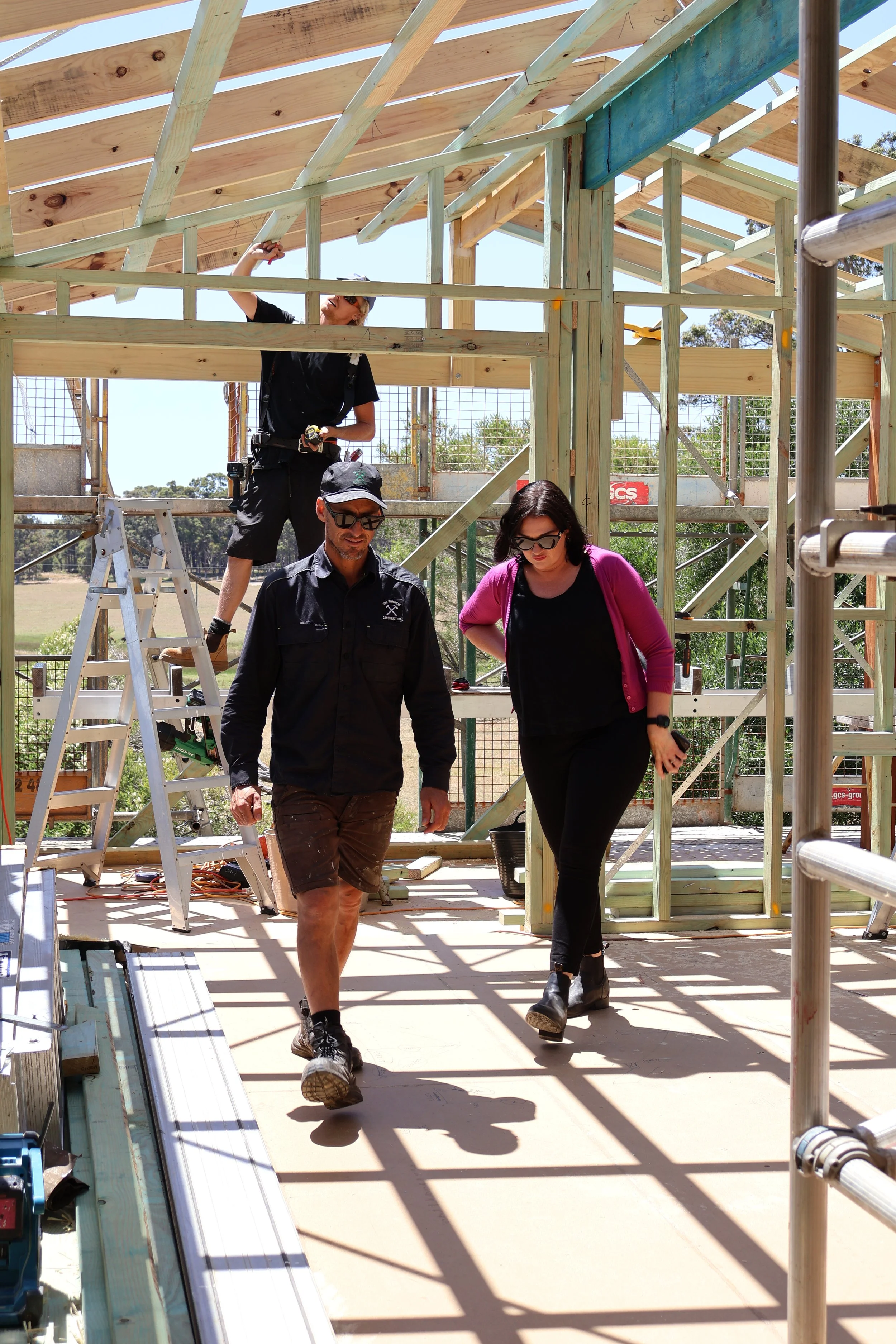 Construction workers building a wooden house frame outdoors under sunlight.