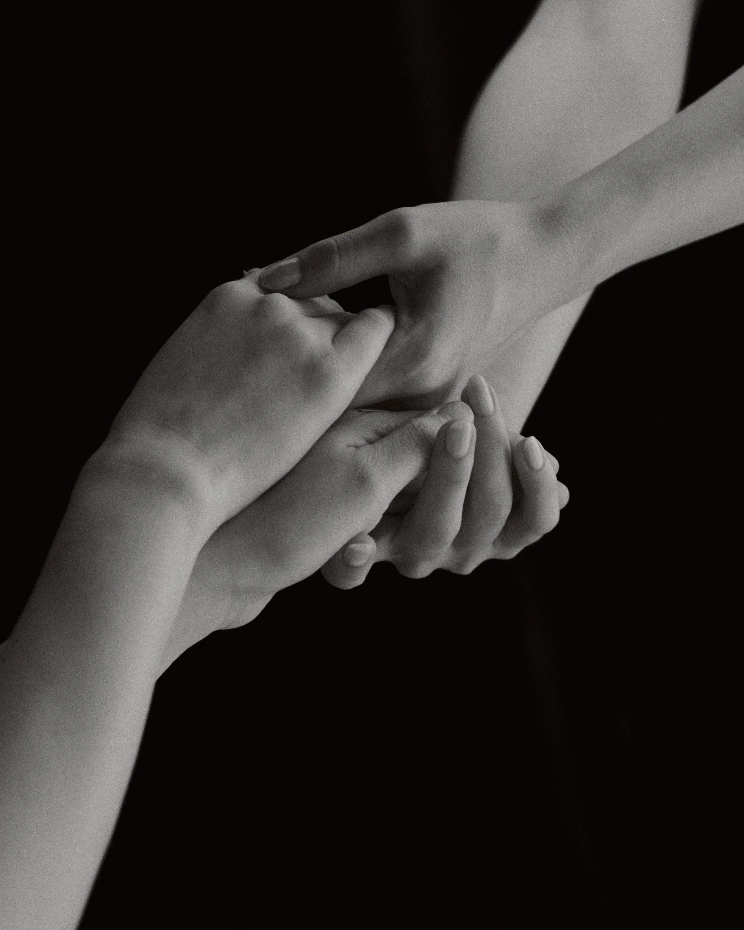 Two hands holding each other in a gentle and caring manner, black and white photo.
