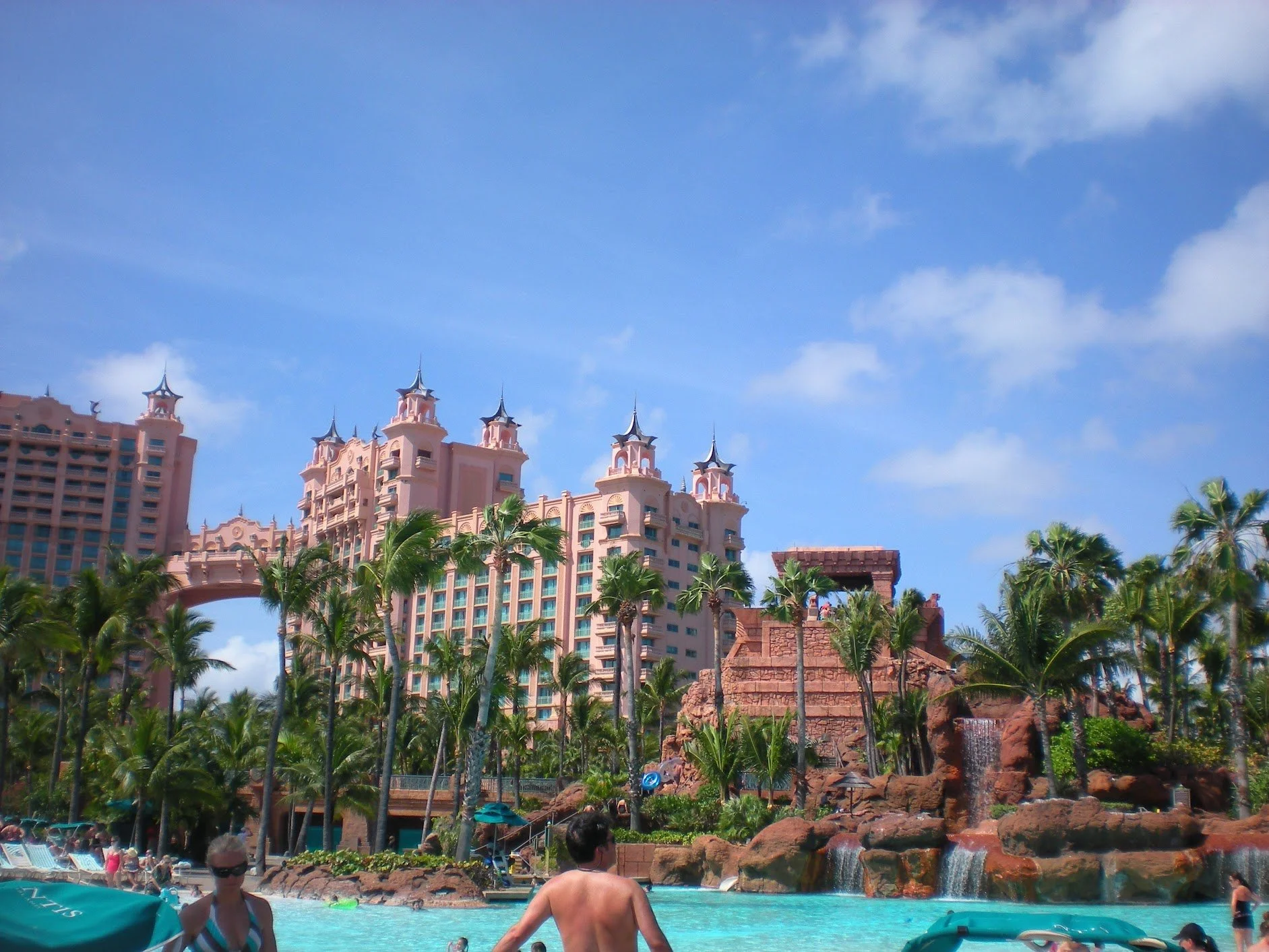 Four partiers pose with drinks in front of a DJ booth at Tropicana Day Club in Mykonos.