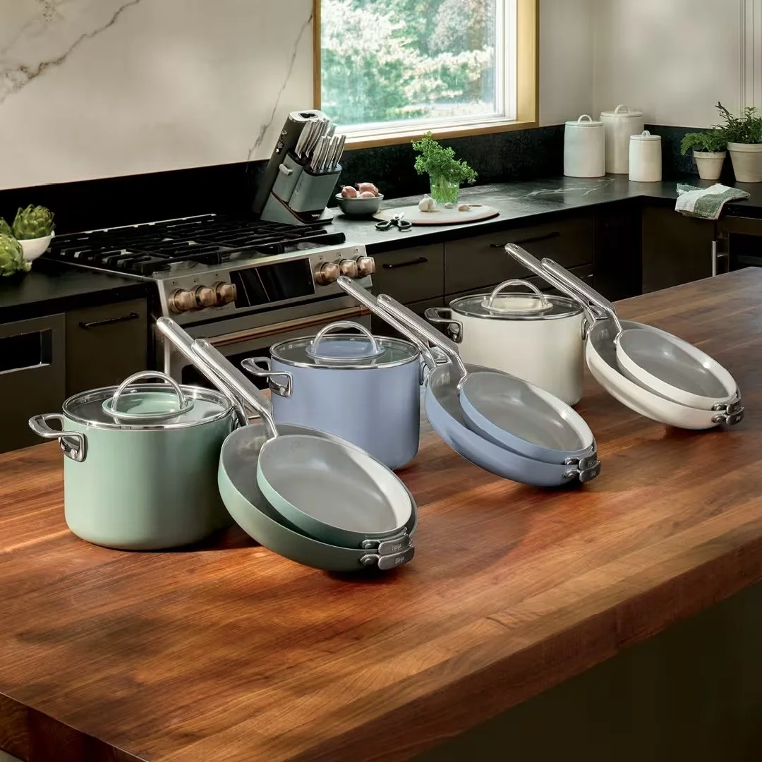 Ninja NeverQuit ceramic cookware sets in green, blue and white displayed on a kitchen island.