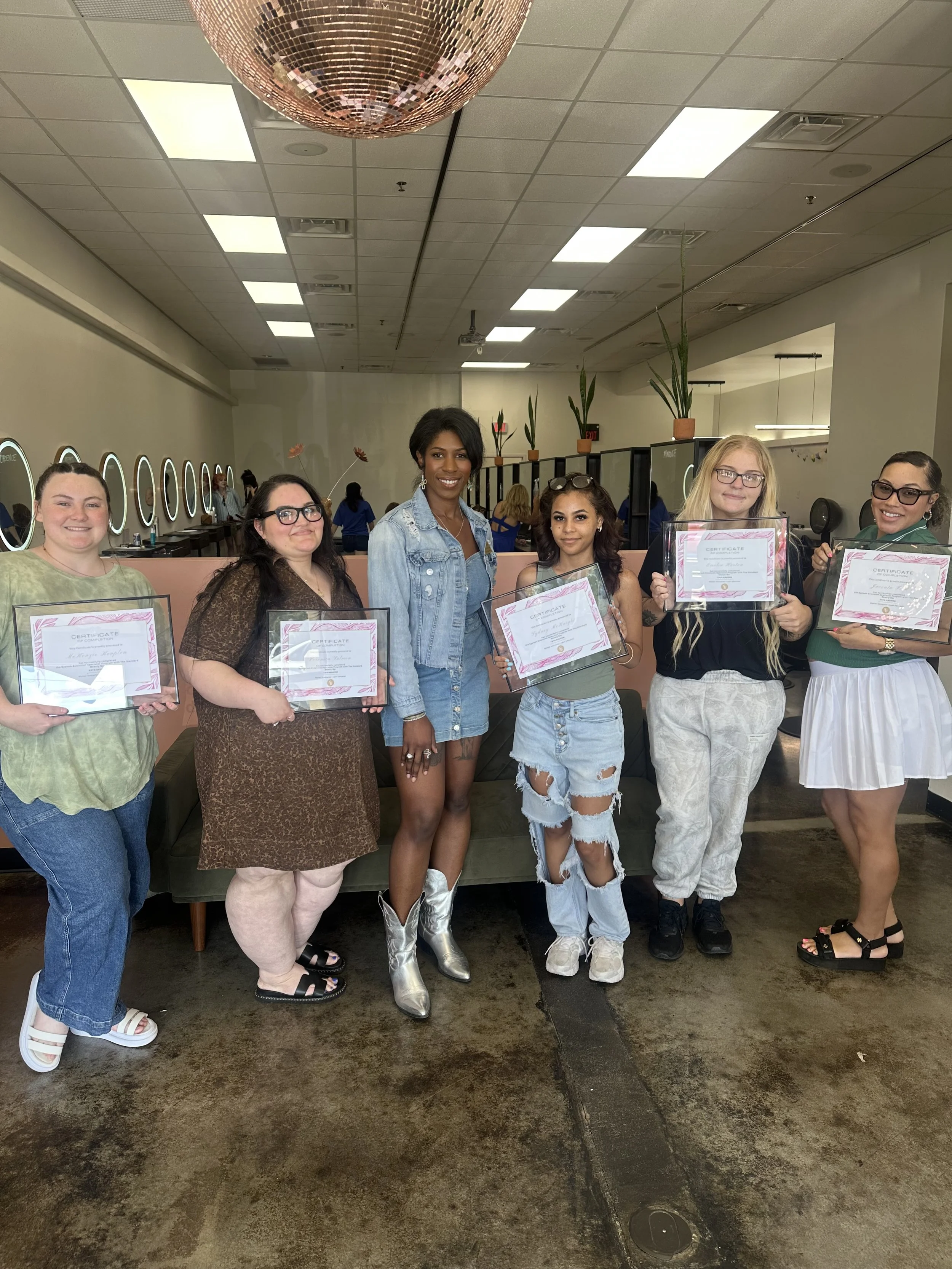 Yaya the instructor standing with graduates of the lash program