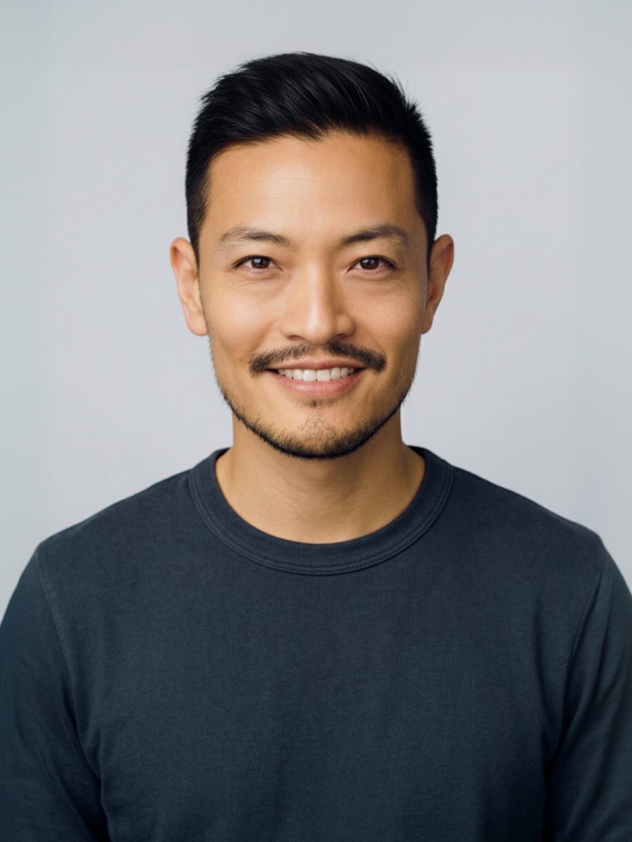 Headshot of a smiling man with short black hair, a mustache, goatee, and wearing a dark gray shirt