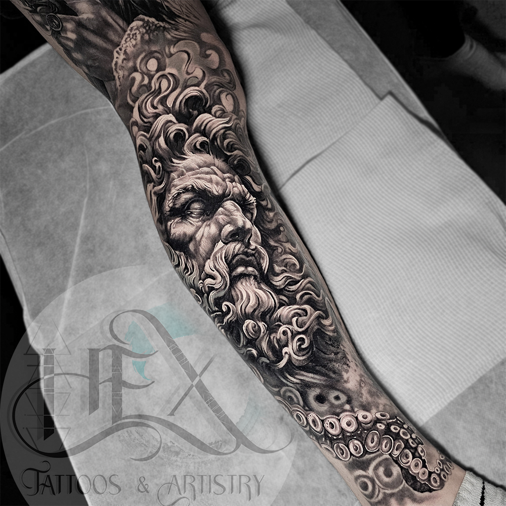 Black and gray tattoo of a Greek god with a beard and flowing hair on a person's arm.
