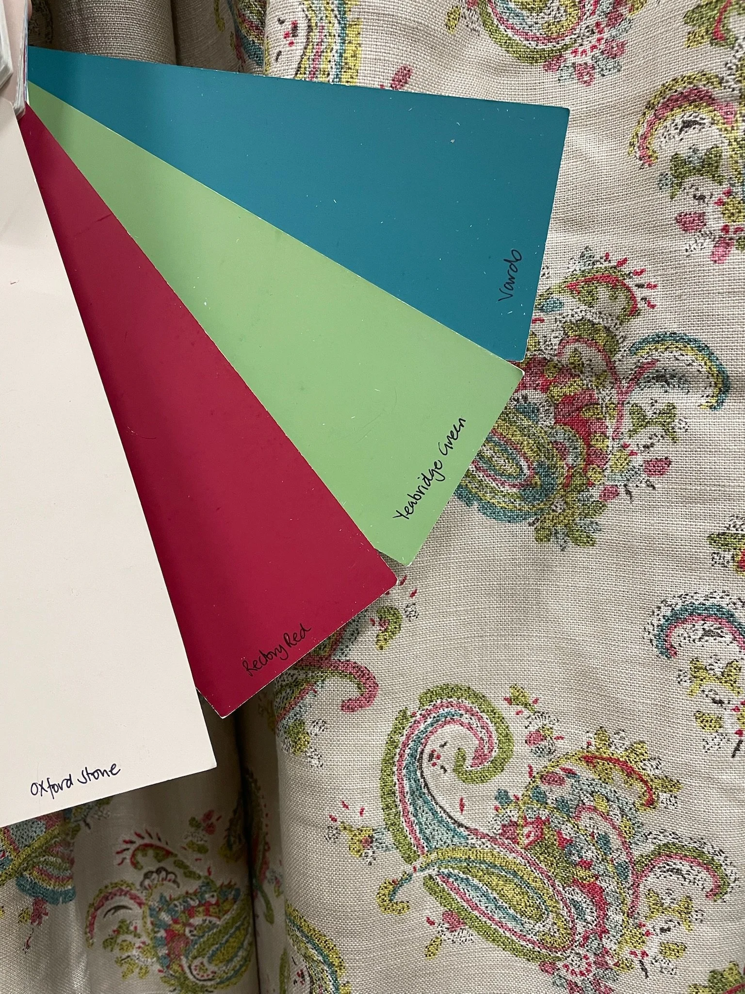 Colorful fabric tablecloth with a paisley pattern and three alphabet cards with handwritten labels: 'Oxford Stone', 'Teardrop', and 'Rebby Red'.