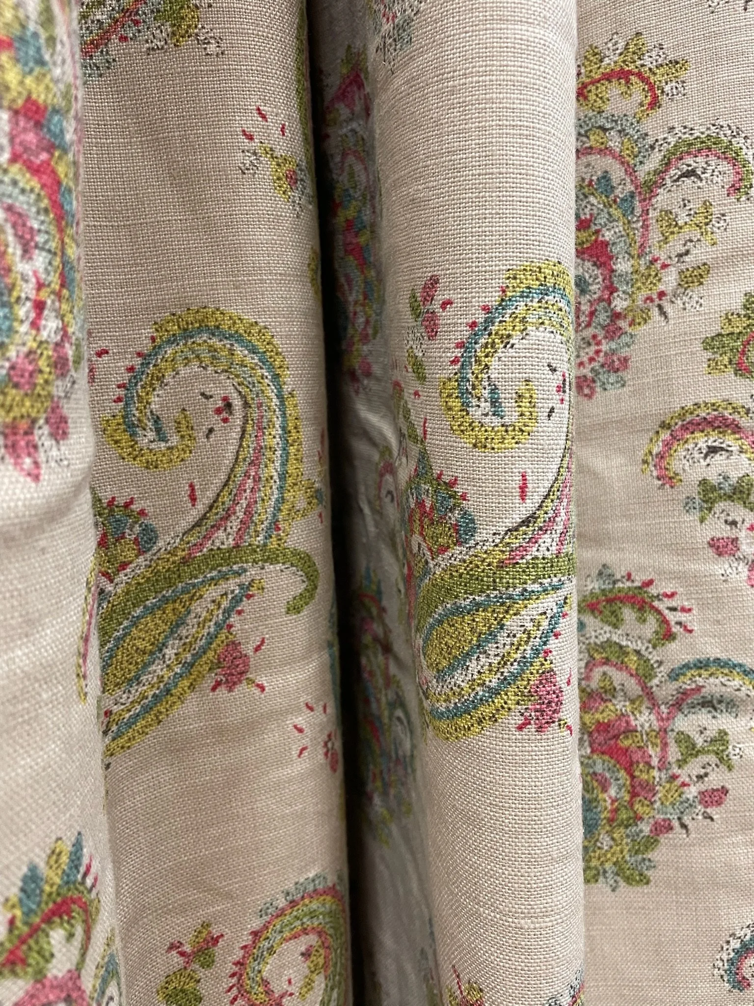 Close-up of floral patterned fabric with pink, green, blue, yellow, and black embroidered details.