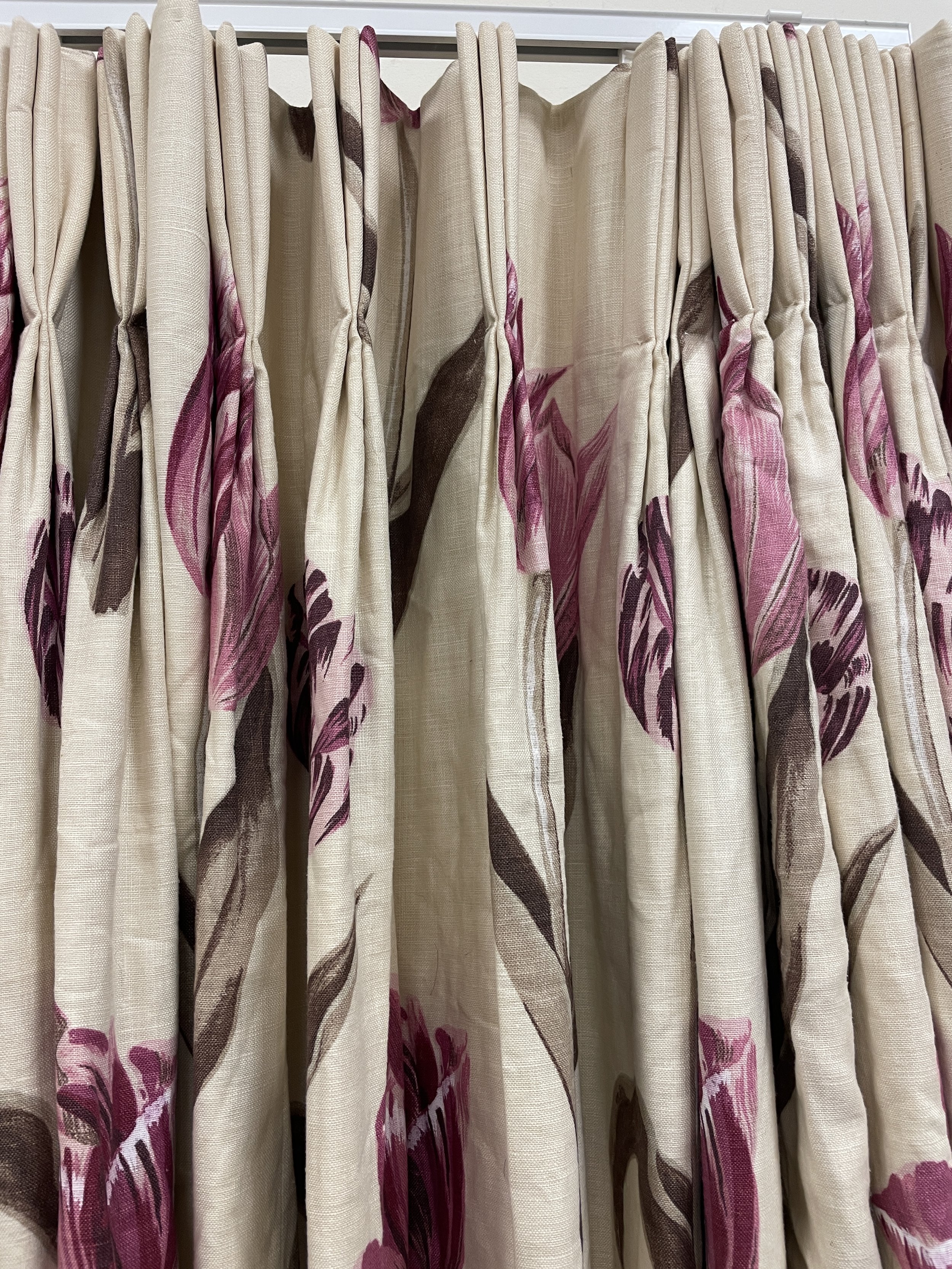 Beige pink and brown floral curtains hanging on a track