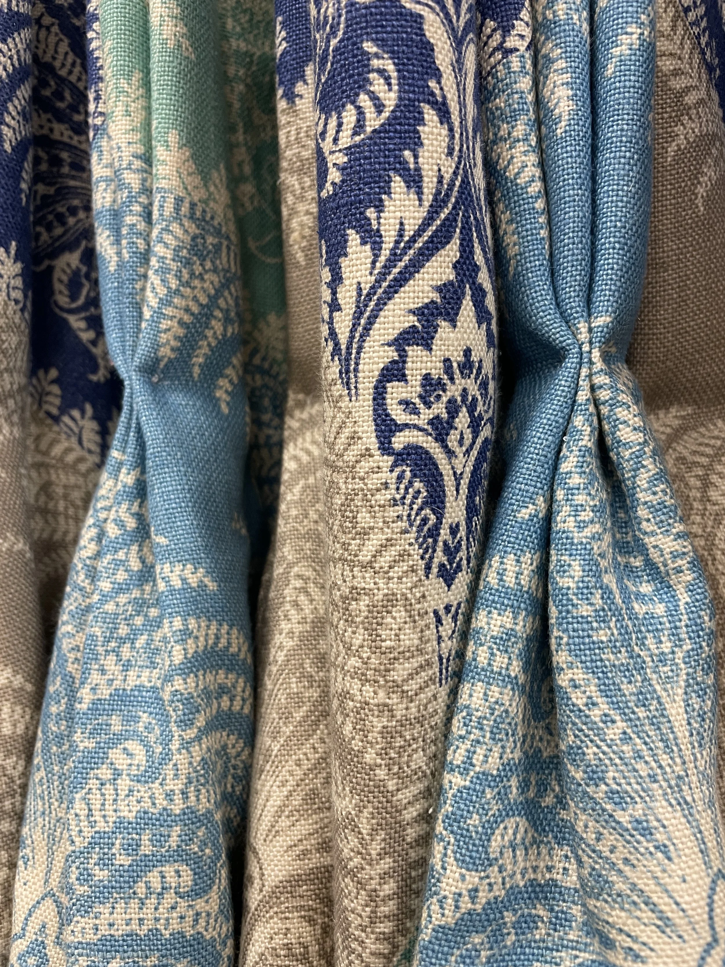 Close-up of blue, white, and beige patterned fabric with floral and nature-inspired design.