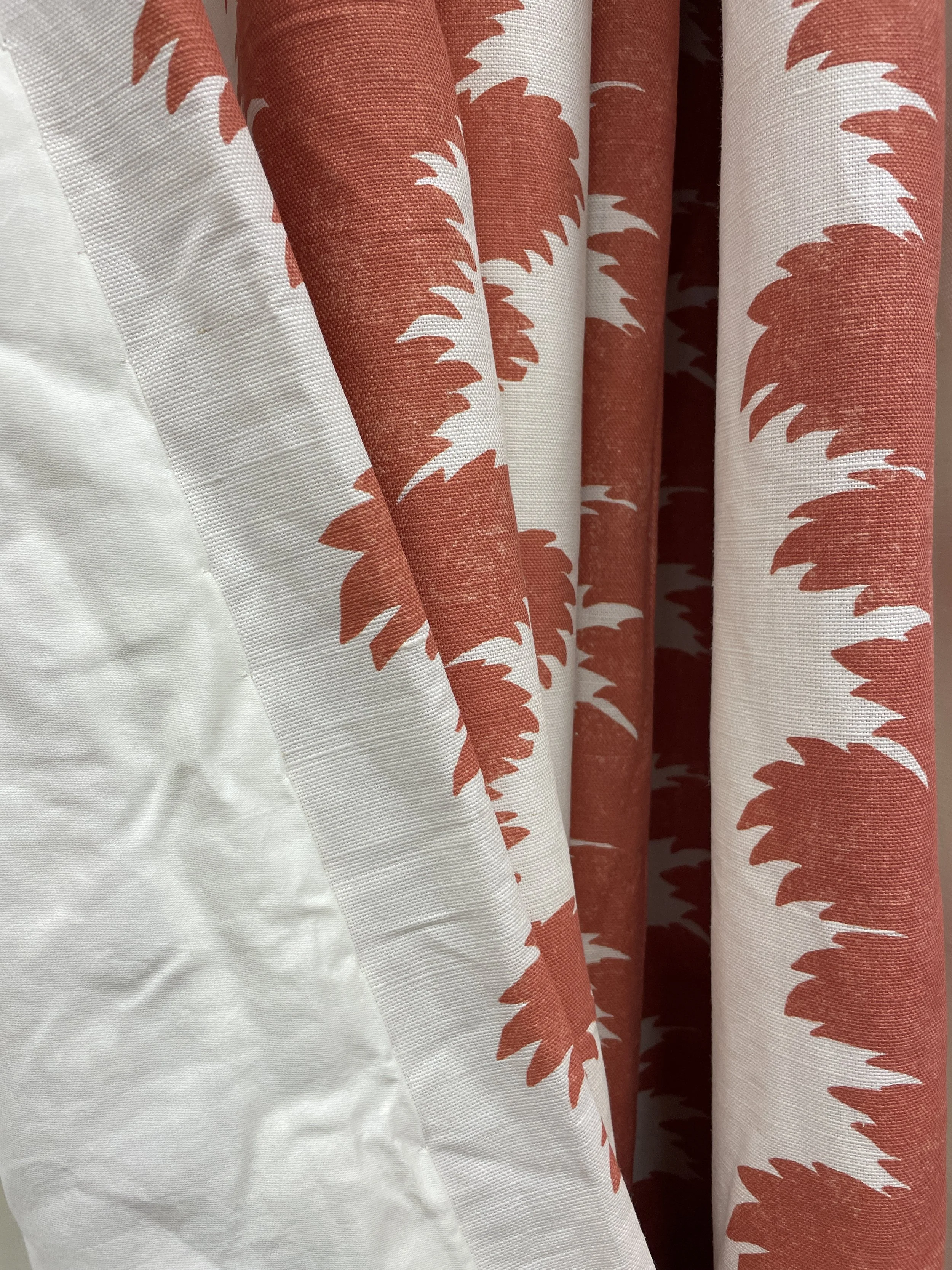 Close-up of a curtain with a white background and orange leaf-like pattern.