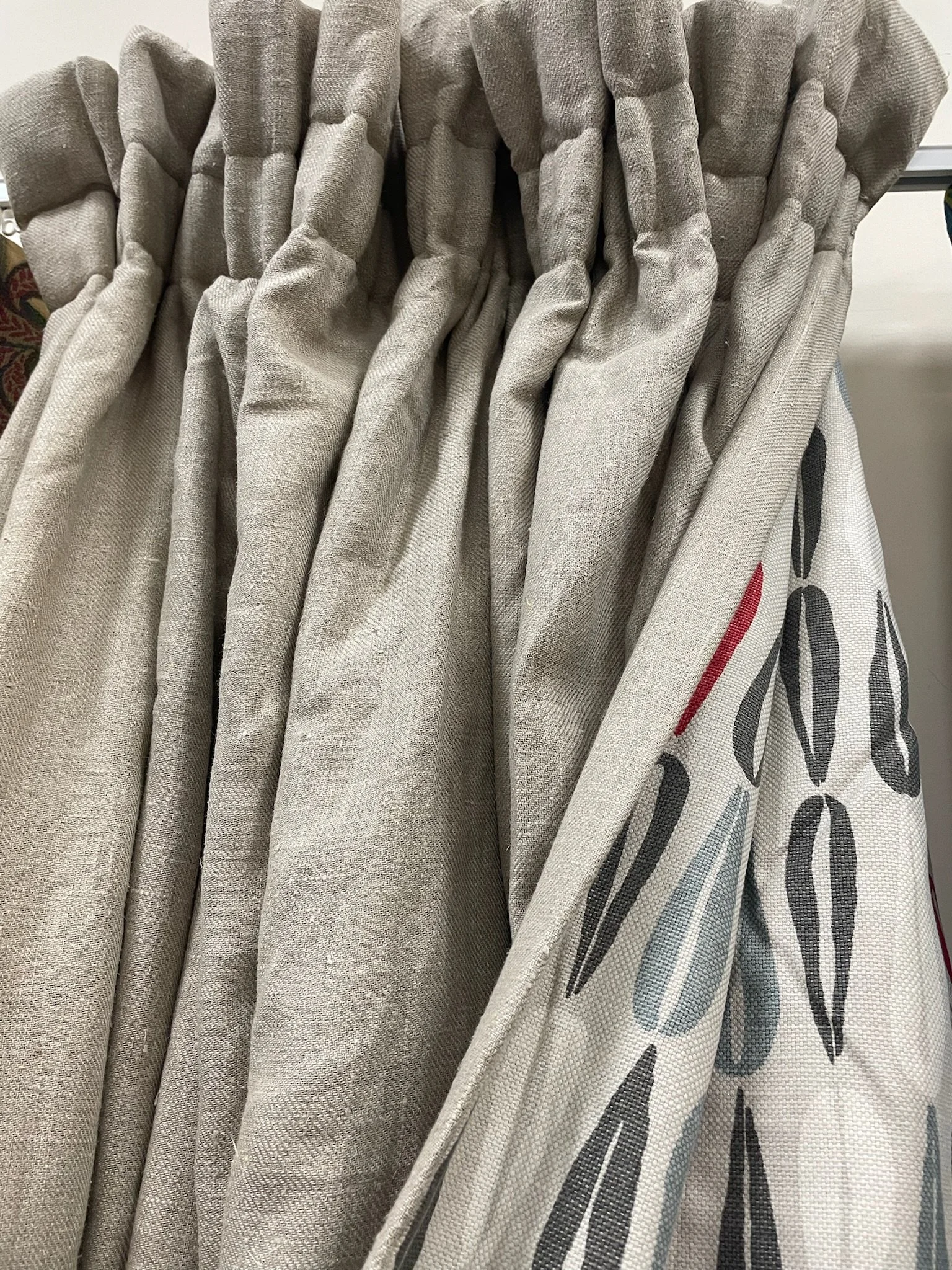 A close-up of a fabric curtain, showing gathered folds and part of printed text.