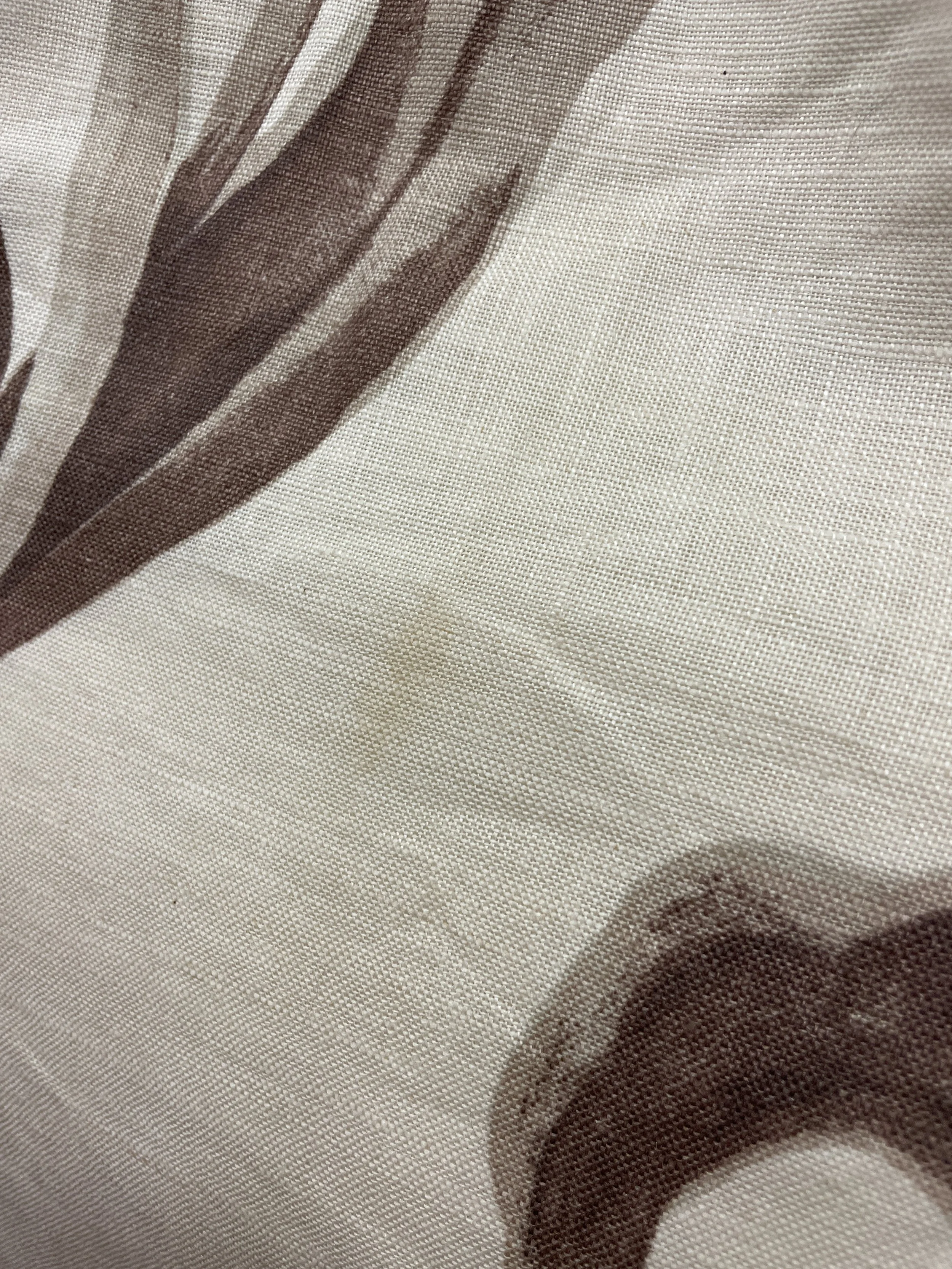 Close-up of a sheer, beige fabric with a brown floral pattern and a mesh texture.