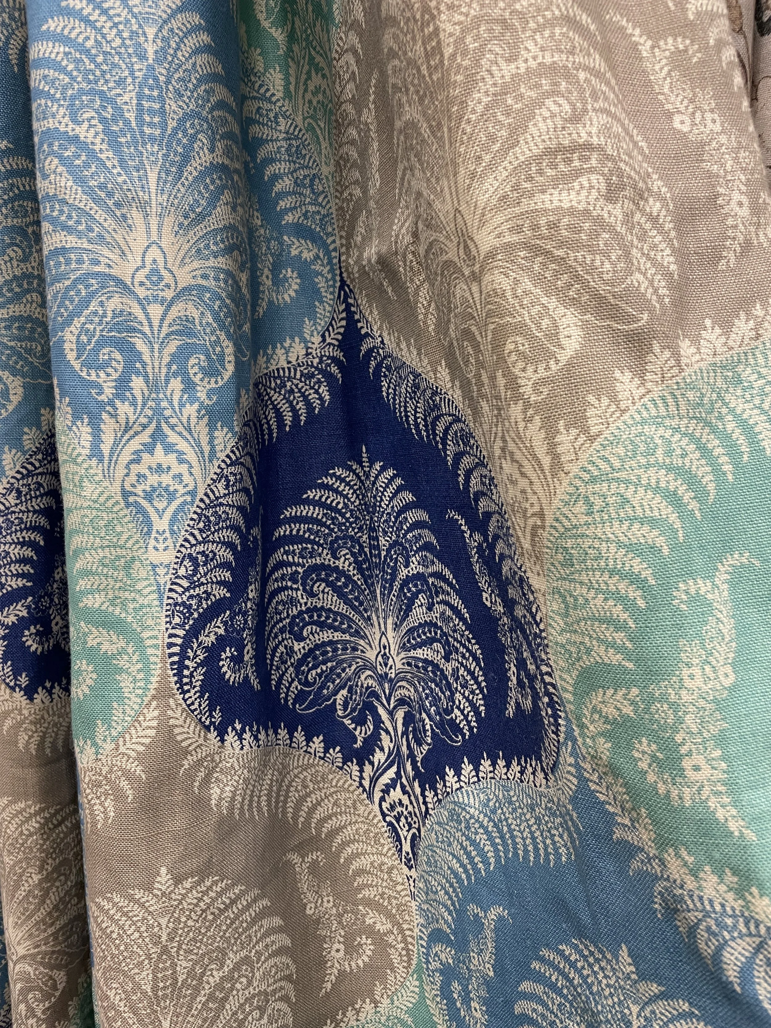 Close-up of fabric with a damask pattern in shades of beige, blue, and teal.