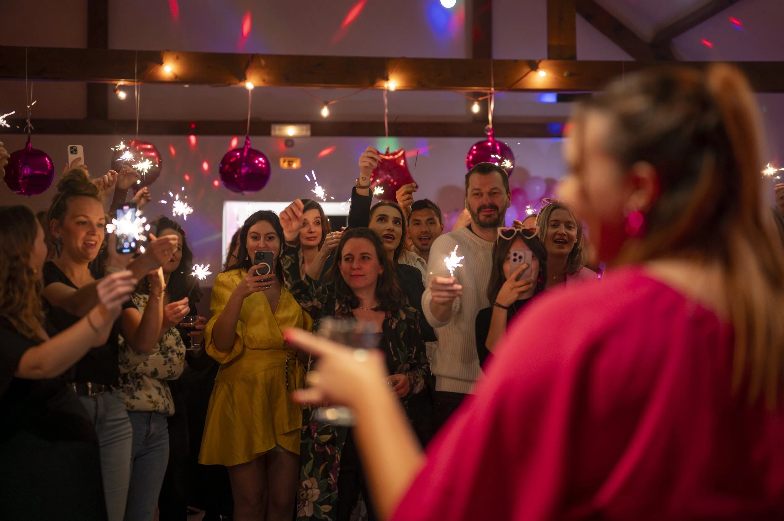 People celebrating at a party with sparklers, balloons, and festive decorations.