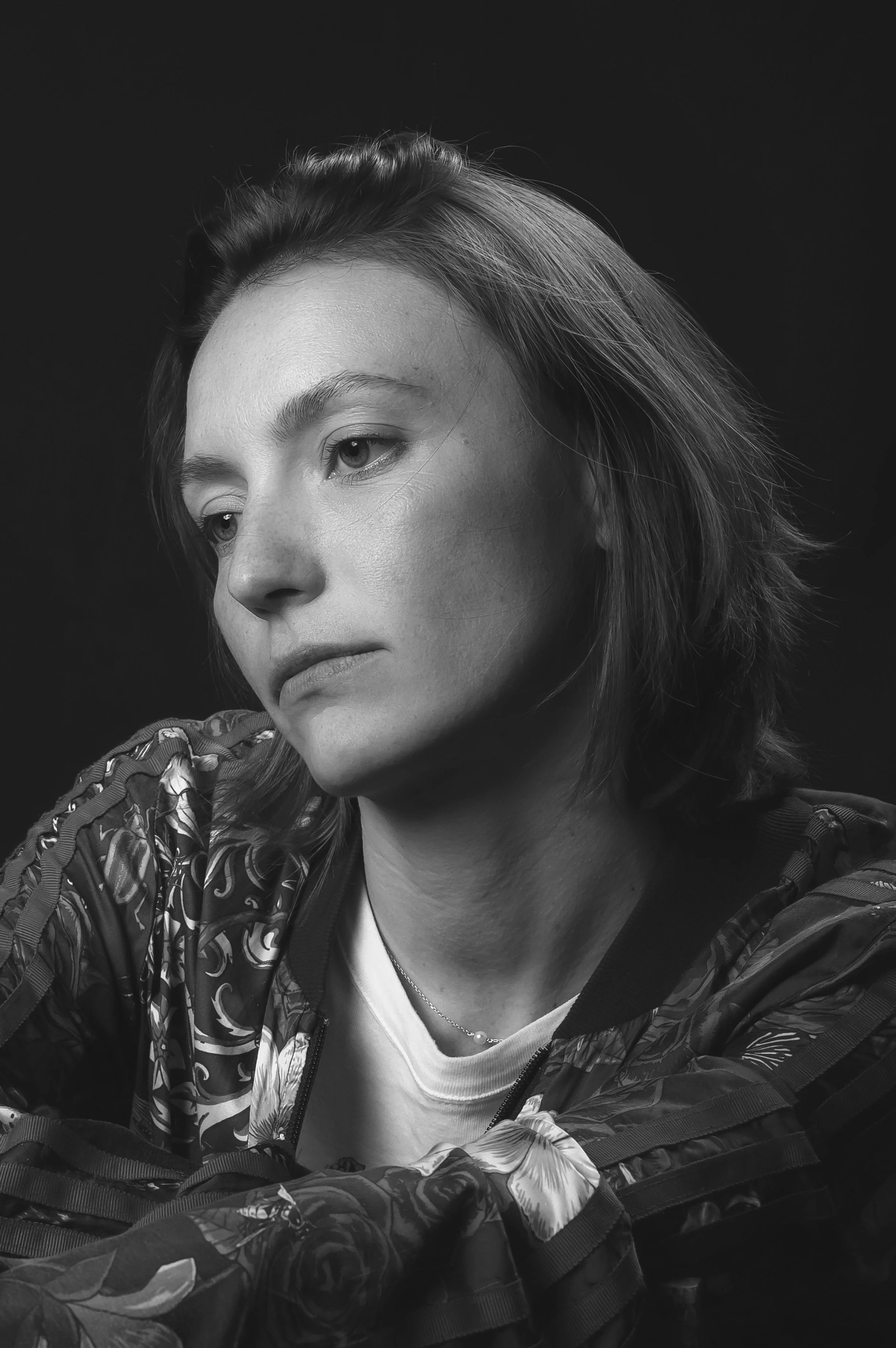 Portrait noir et blanc d’une femme regardant sur le côté, fond sombre.