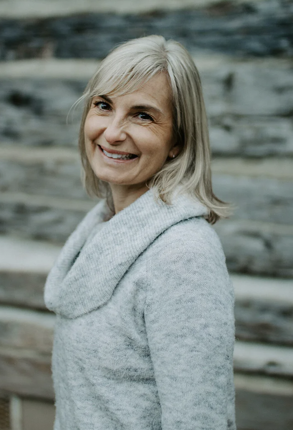 Woman smiling wearing a grey turtleneck sweater