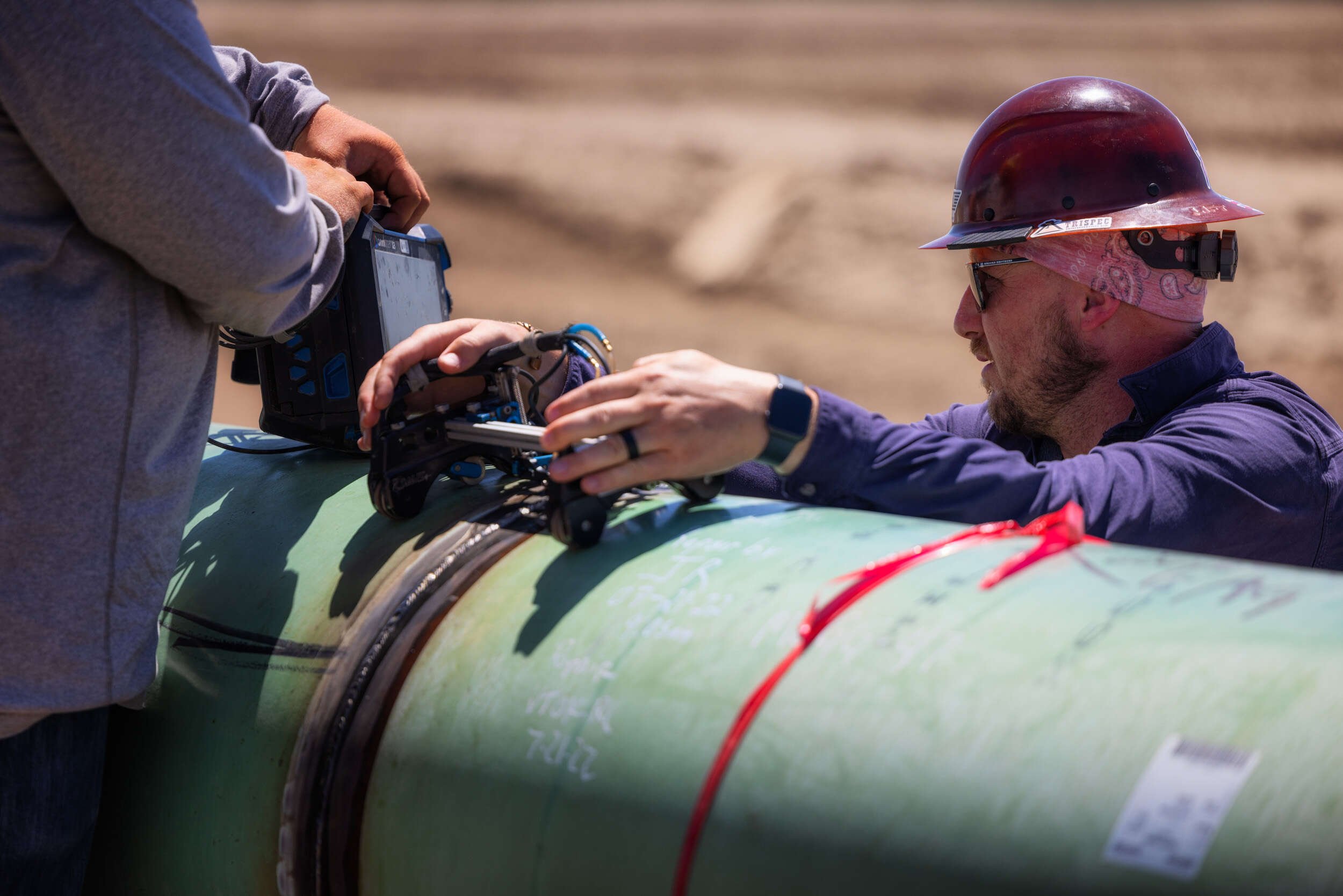 A technician checking the pipeline weld integrity using a phased array ultra sonic monitor