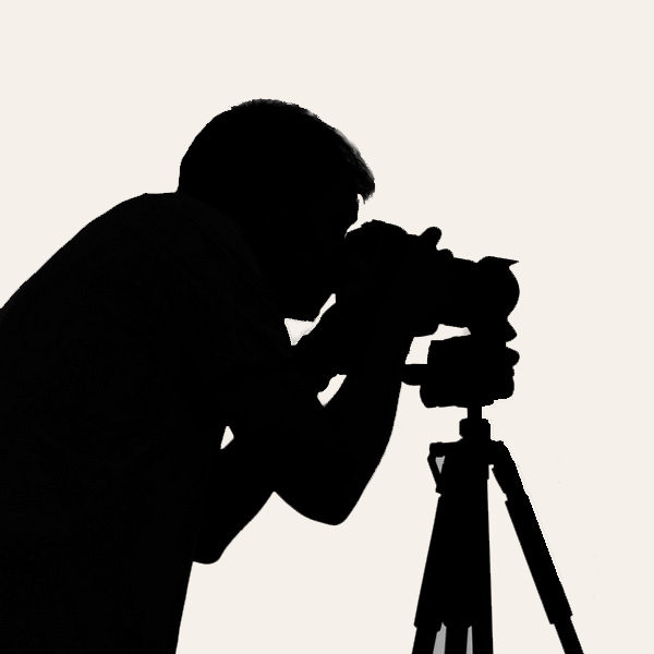 Silhouette of a person using a camera on a tripod