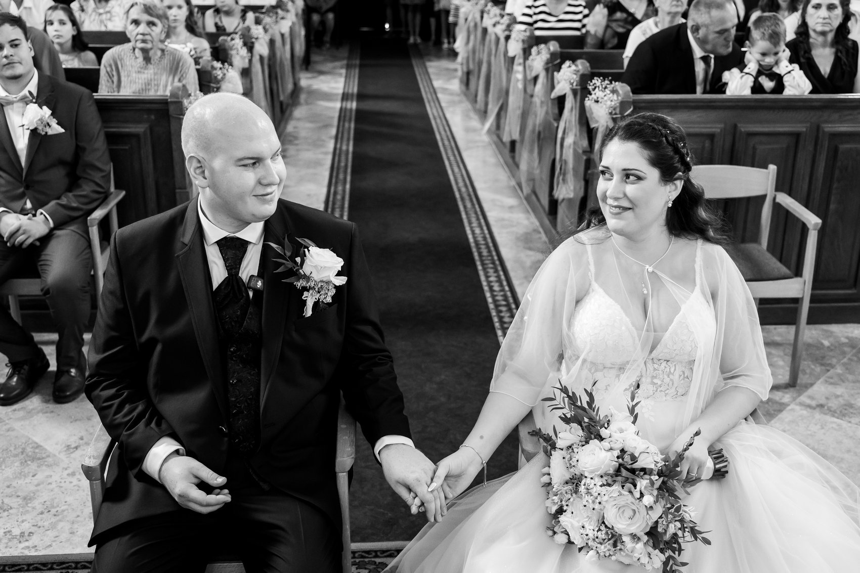 A bride and groom embracing in front of a detailed stone cathedral entrance with carved figures and decorative patterns.