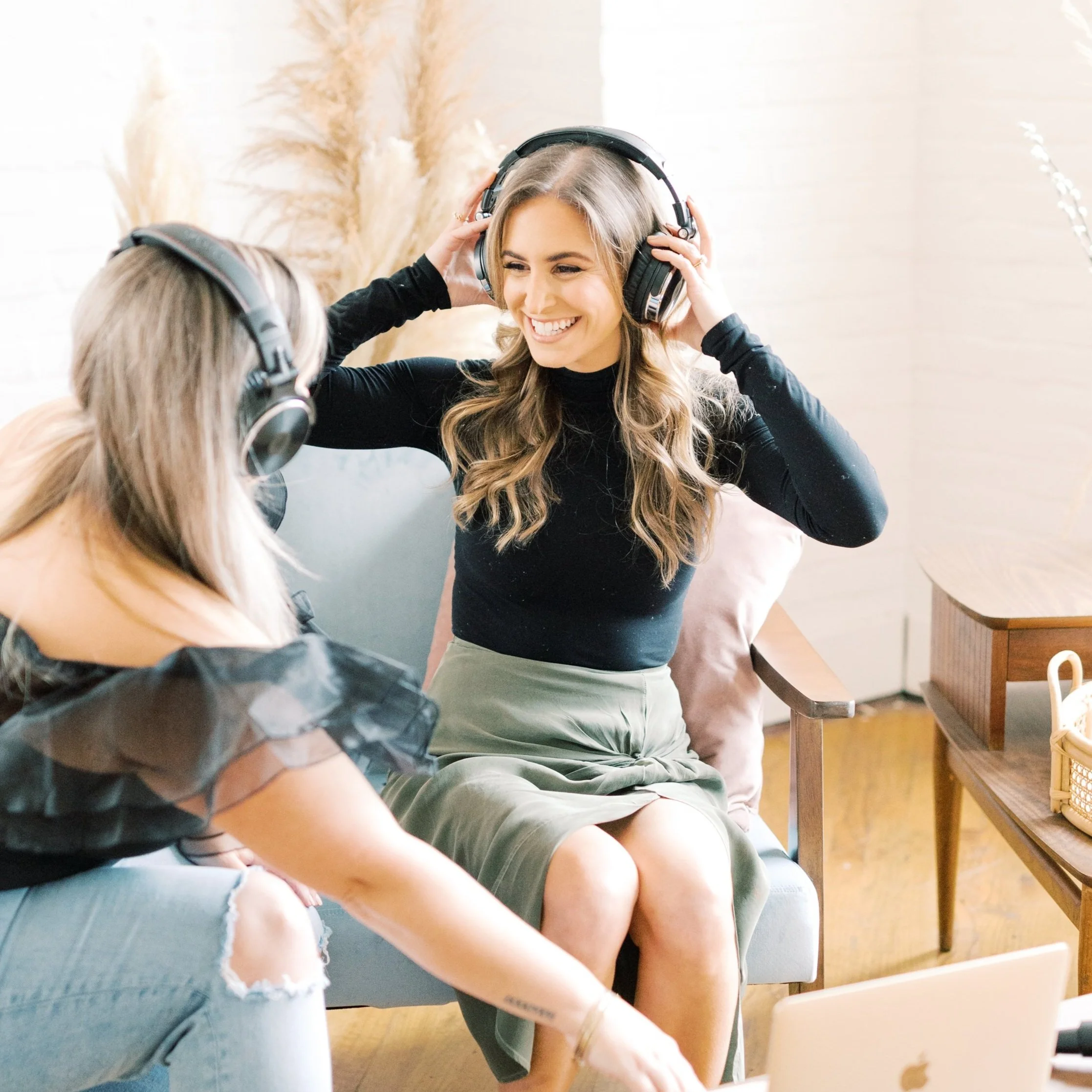 Smiling woman wearing headphones while friends gather around her indoors