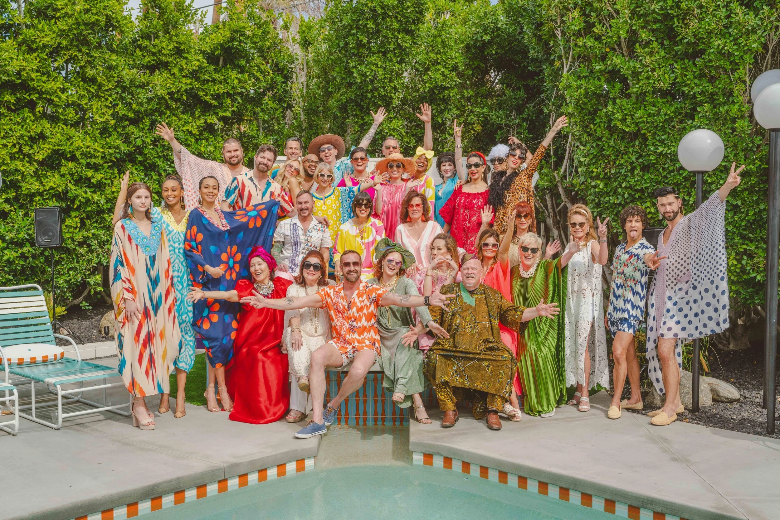 A vintage black Dodge car parked in front of a modern white wall with a green door and palm trees in the background on a sunny day.