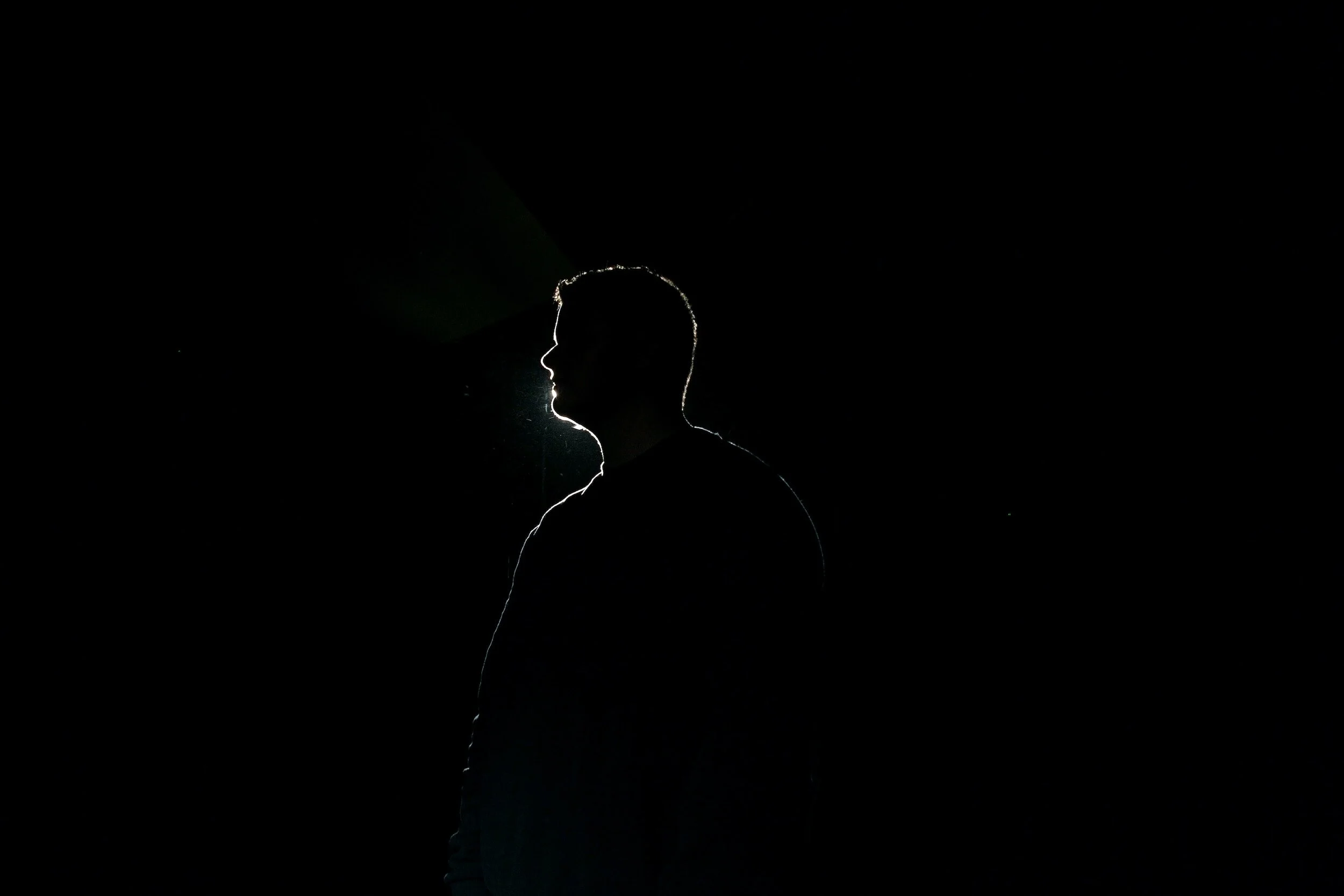 Silhouette of a person with backlighting, surrounded by dark, empty space.