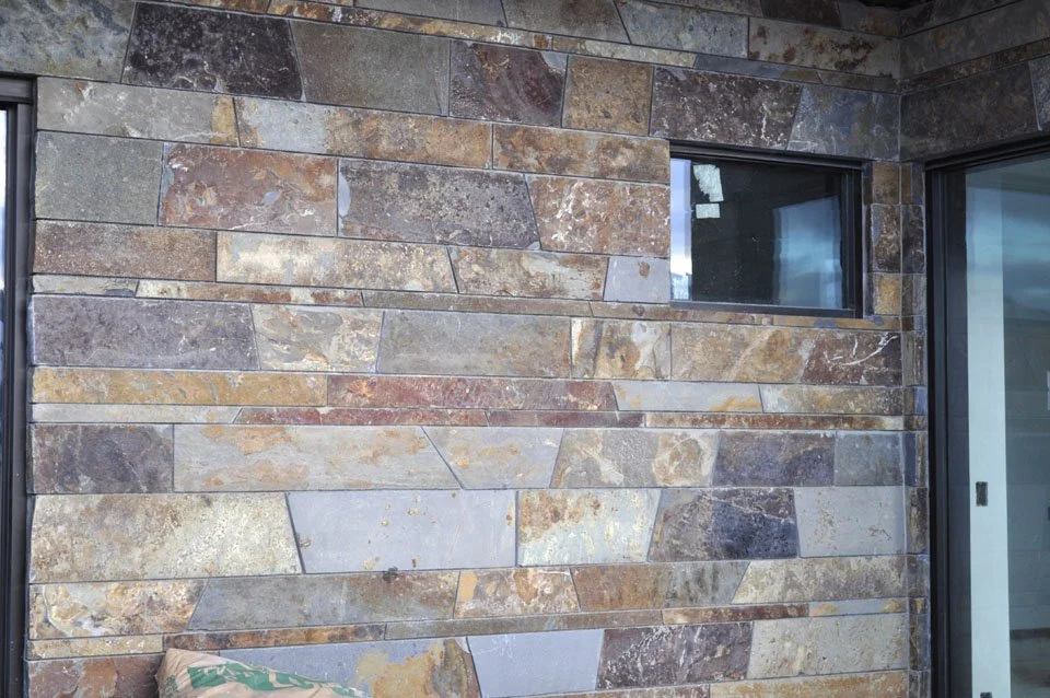 A wall made of rectangular natural stone tiles with two horizontal windows.