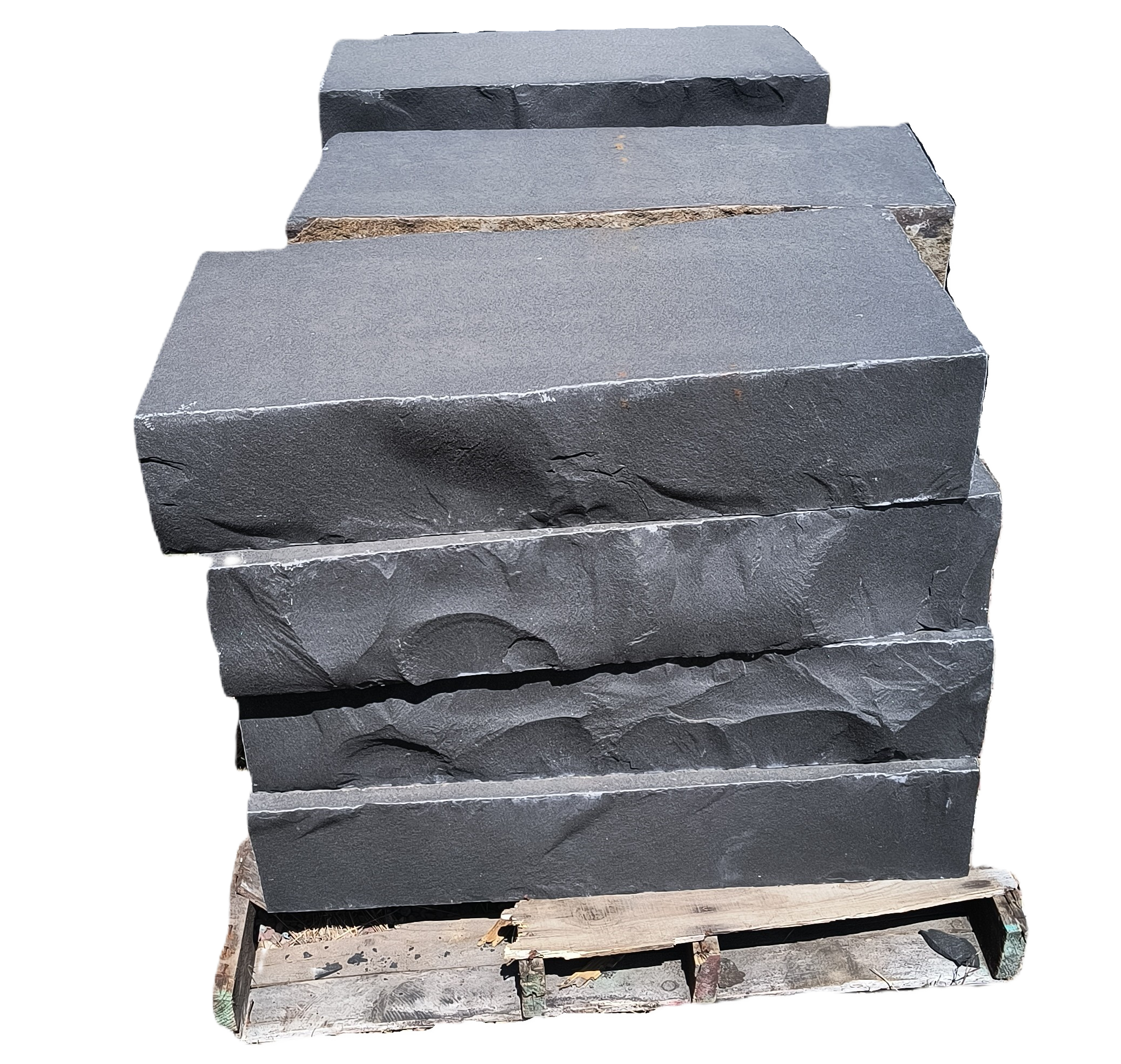 Stacks of large, flat, irregularly shaped stone slabs on wooden pallets in an outdoor yard