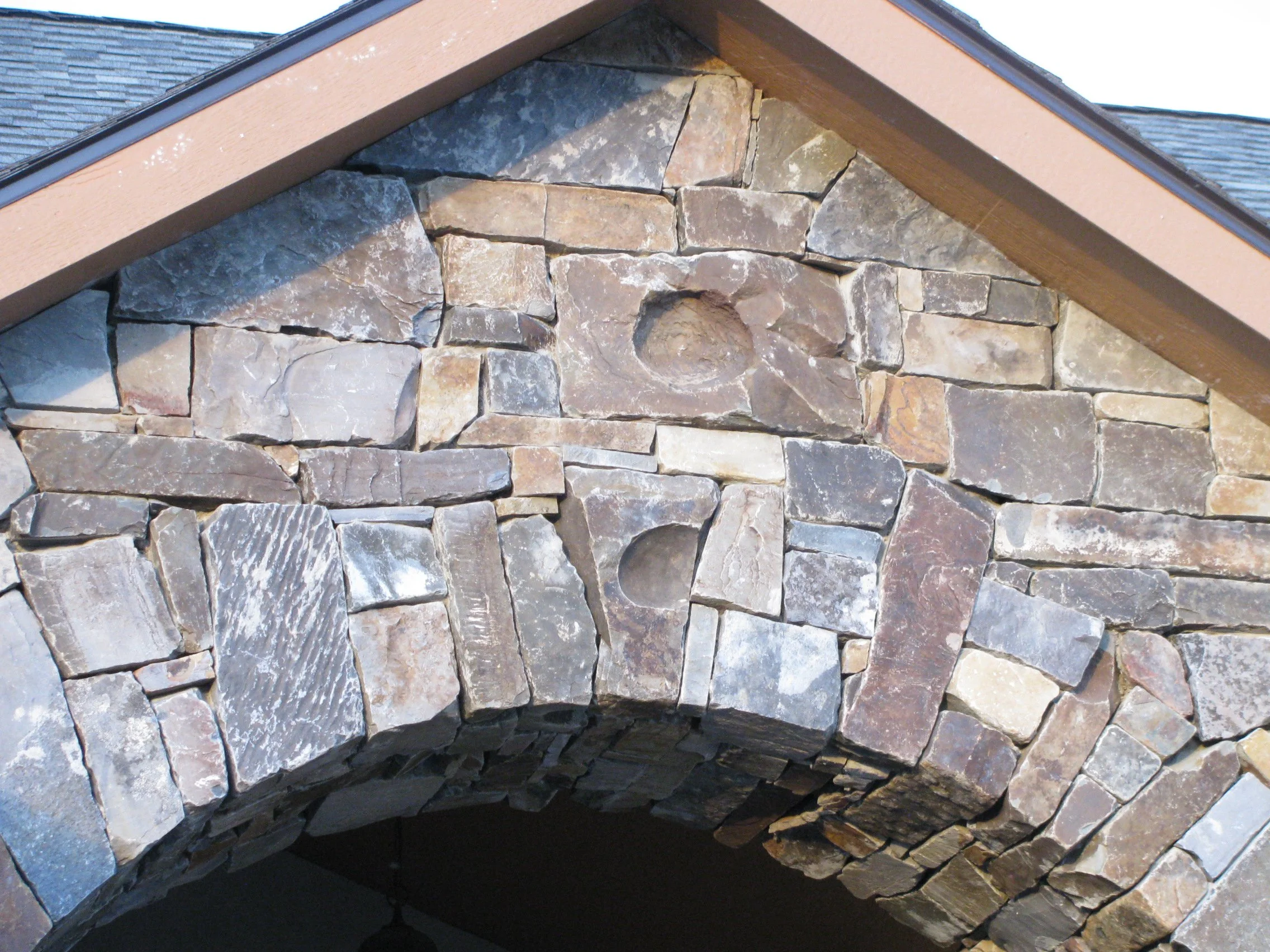 Close-up image of the interior of a chimney made with irregularly shaped stones, showing the opening at the bottom.