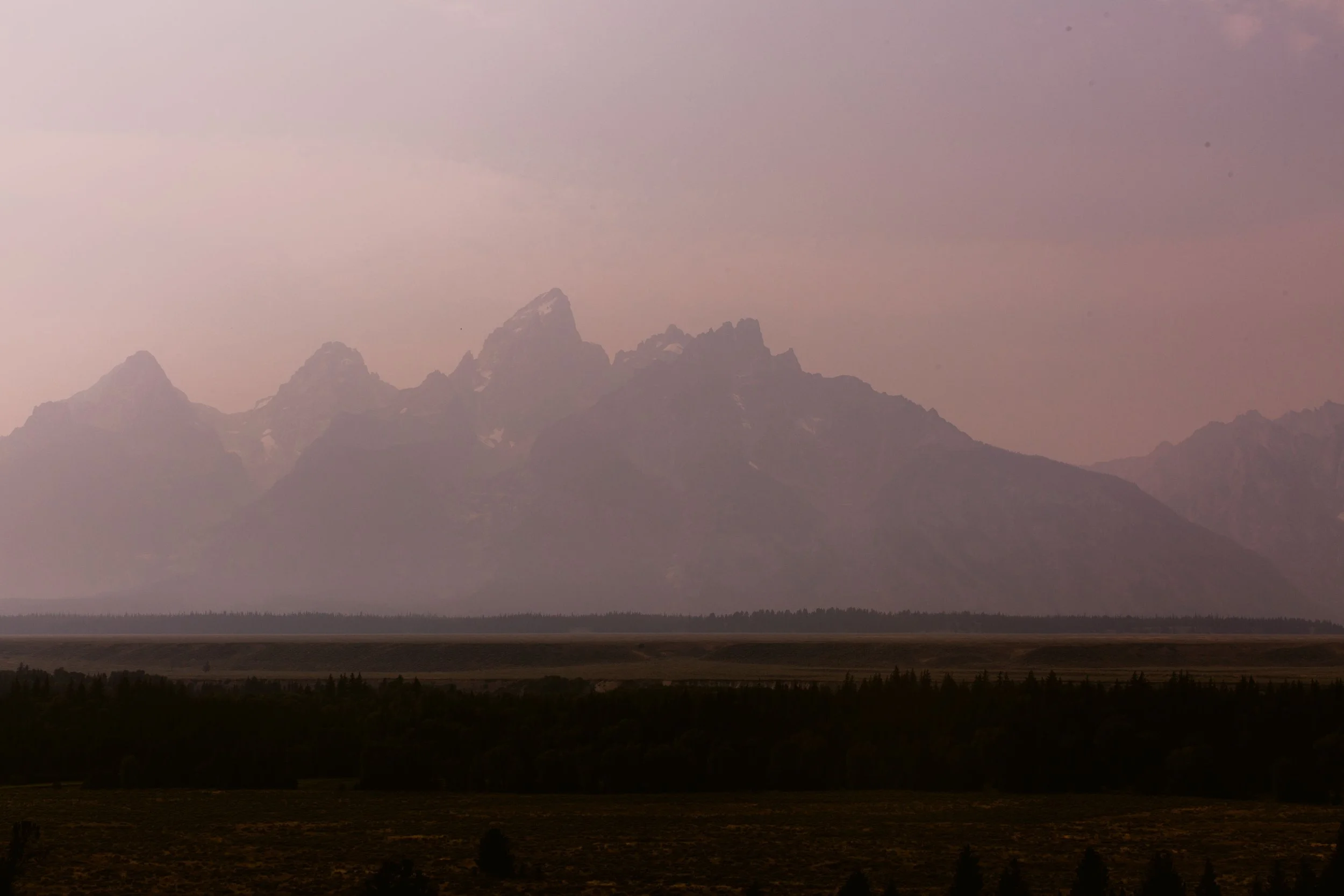 Pink Sunset Smokey view of the Grand Tetons near Diamond Cross Ranch in Wyoming