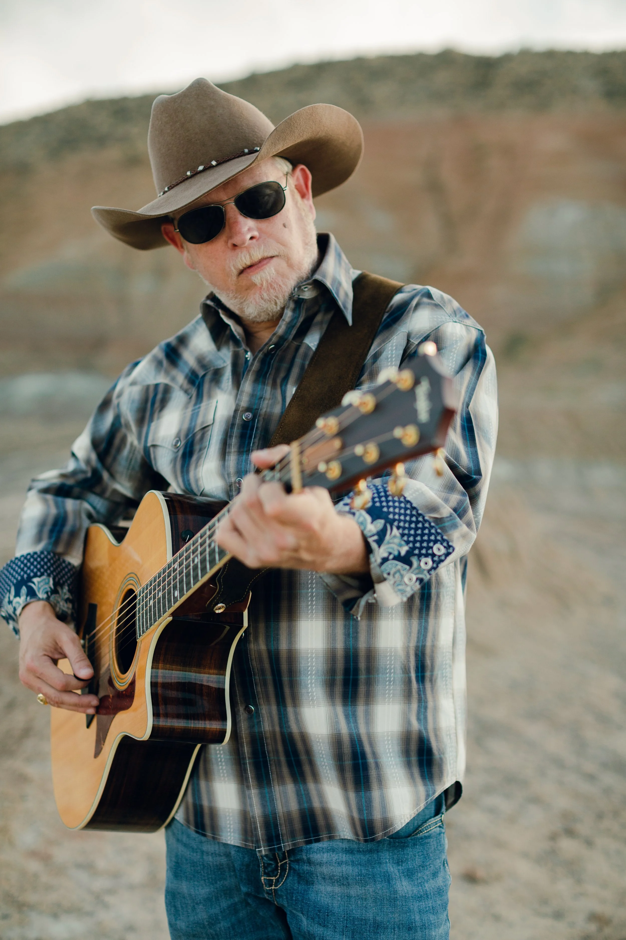 Wyoming musician Aaron Walker playing acoustic guitar during a portrait session in the Badlands near Cody, Wyoming.
