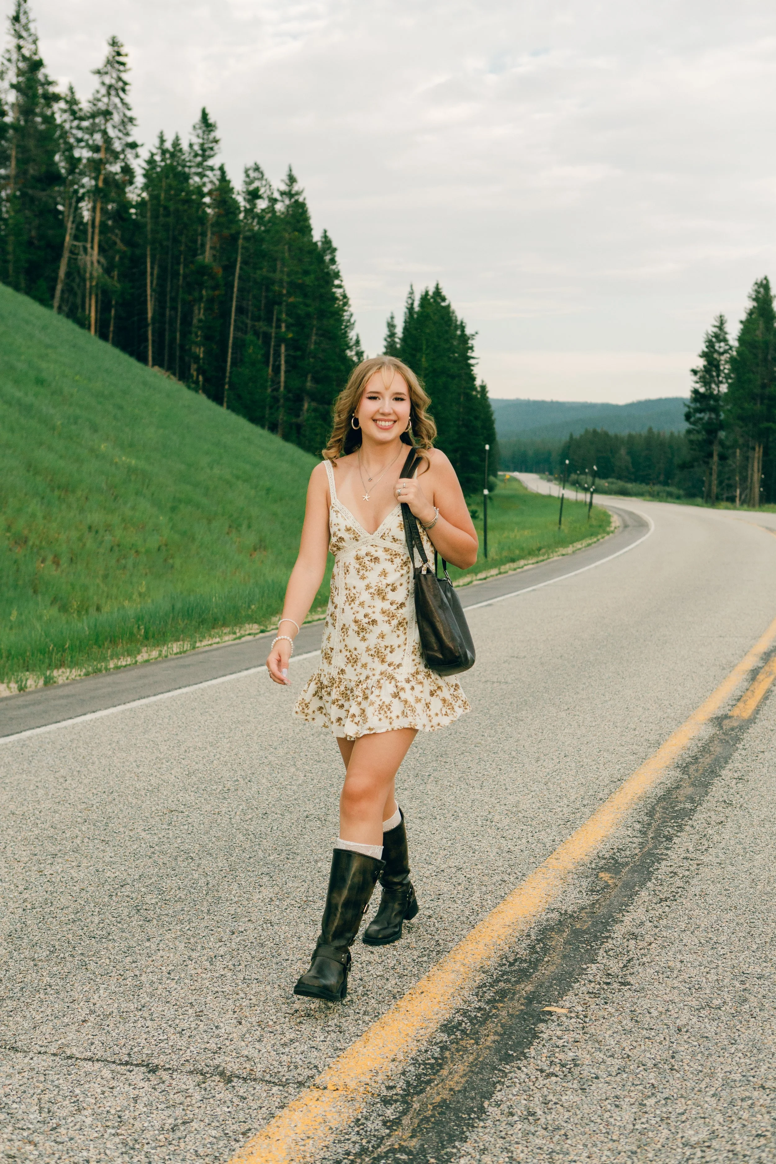 Senior portrait walking along a scenic mountain road in the Big Horn Mountains near Sheridan, Wyoming during a summer evening photo session.