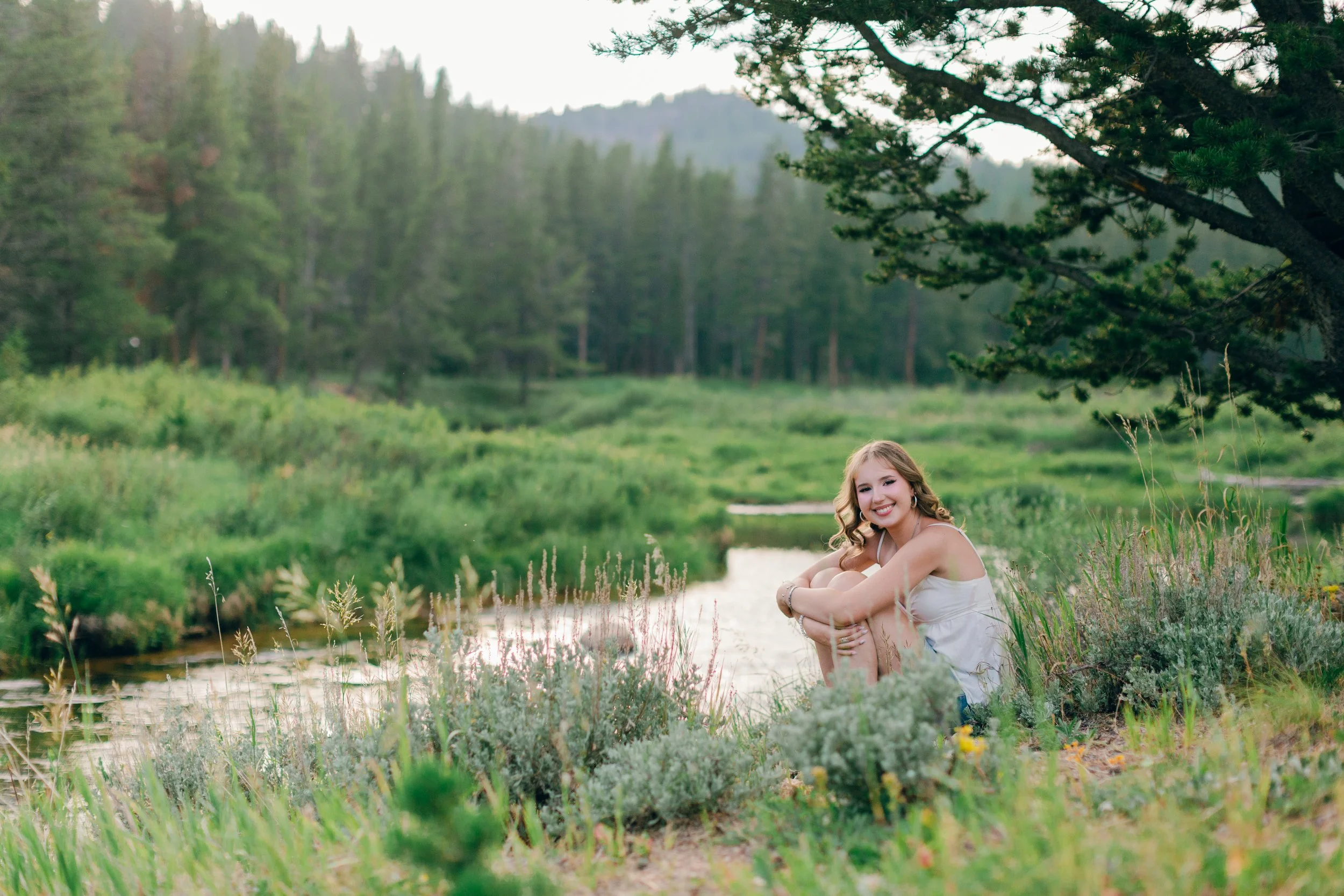 Senior portrait overlooking a mountain river in the Big Horn Mountains near Sheridan, Wyoming during a summer evening photo session.