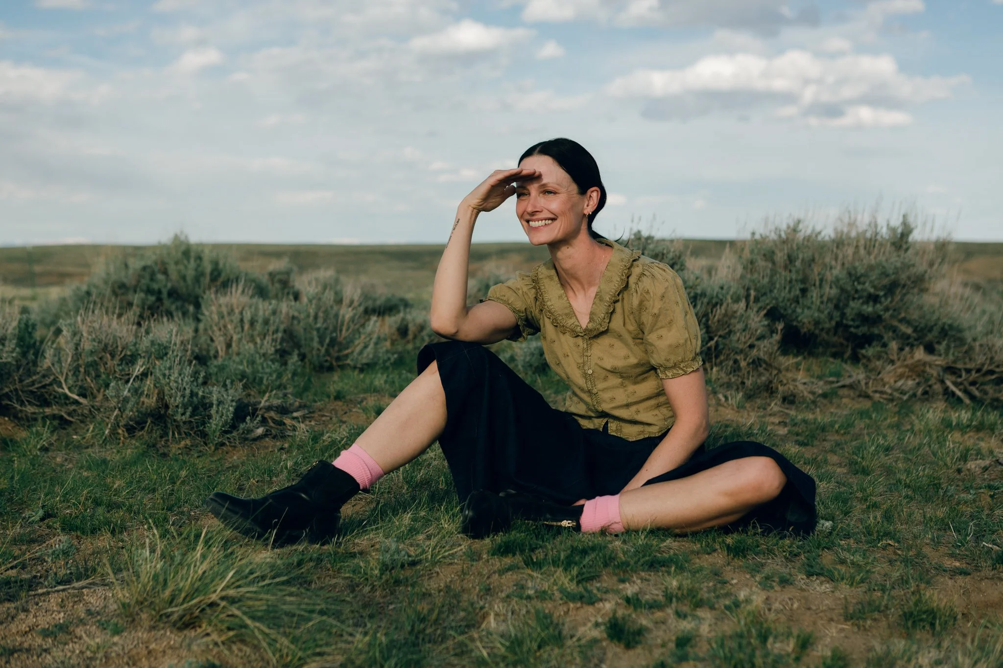 Editorial portrait beside a weathered ranch fence overlooking the McCullough Peaks Badlands near Cody, Wyoming.