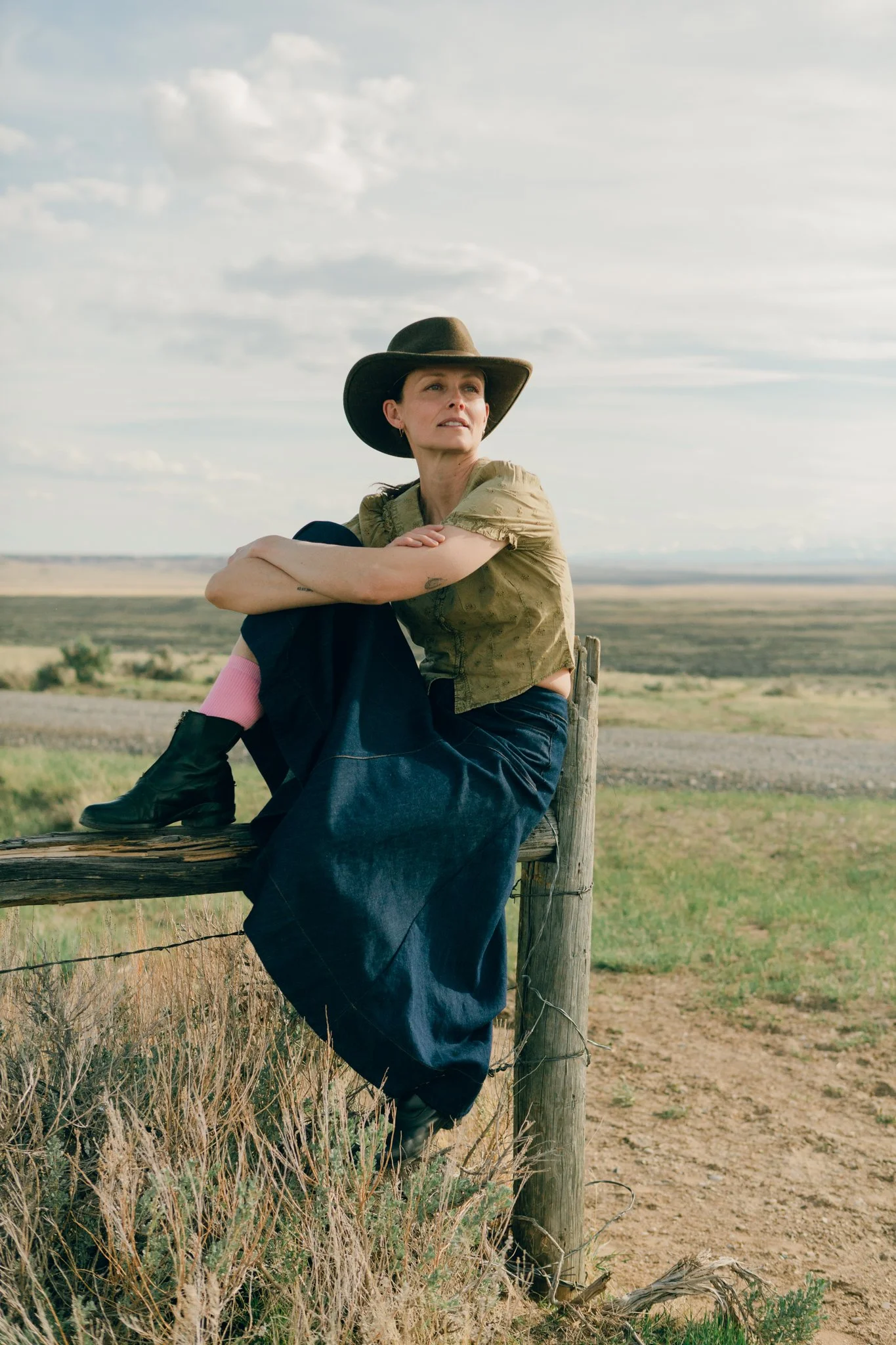 Editorial portrait during a photoshoot in the McCullough Peaks Badlands on a barb wire fence brace near Cody, Wyoming.