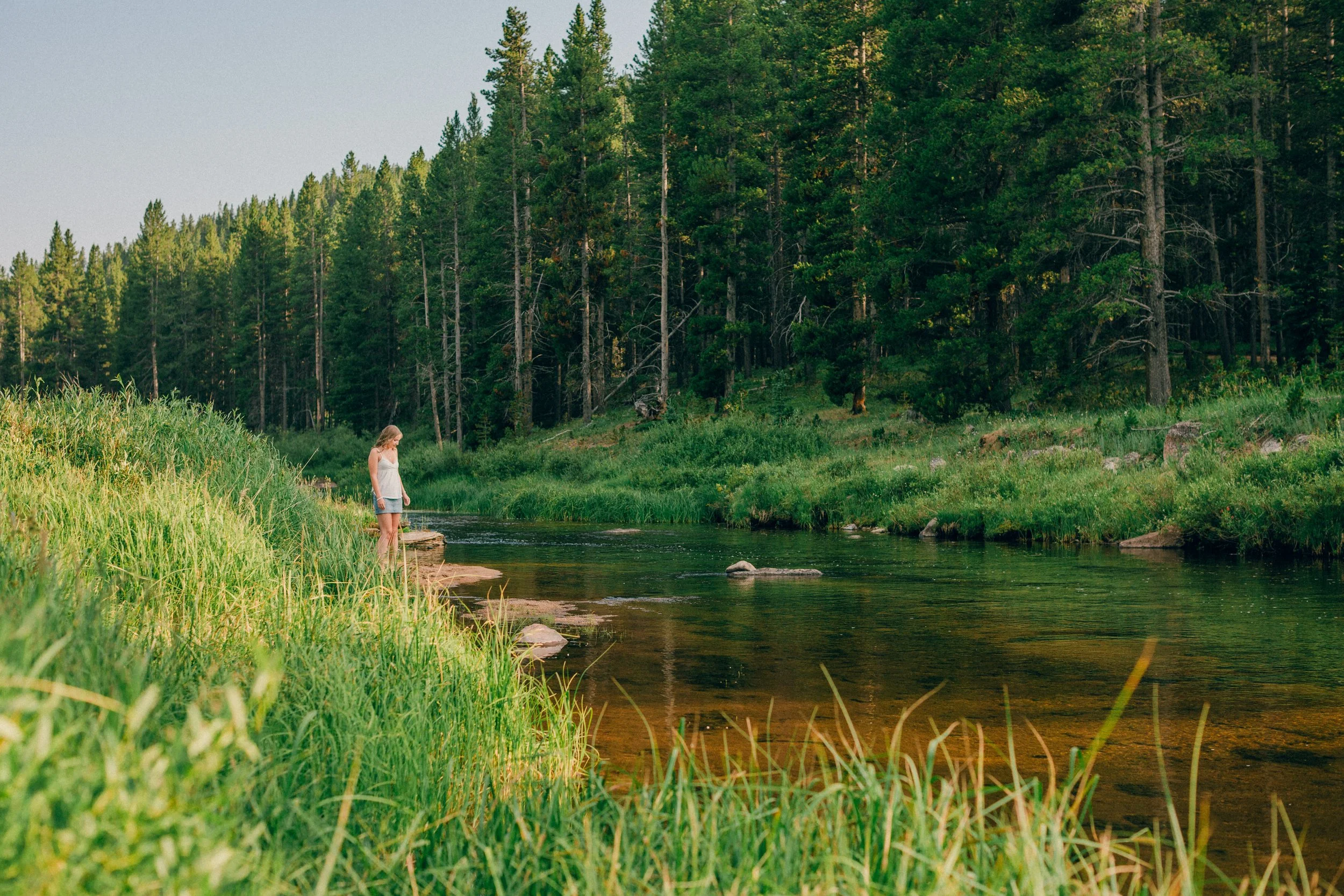 Scouting light and location along a mountain river in the Big Horn Mountains near Sheridan, Wyoming before a summer senior portrait session.