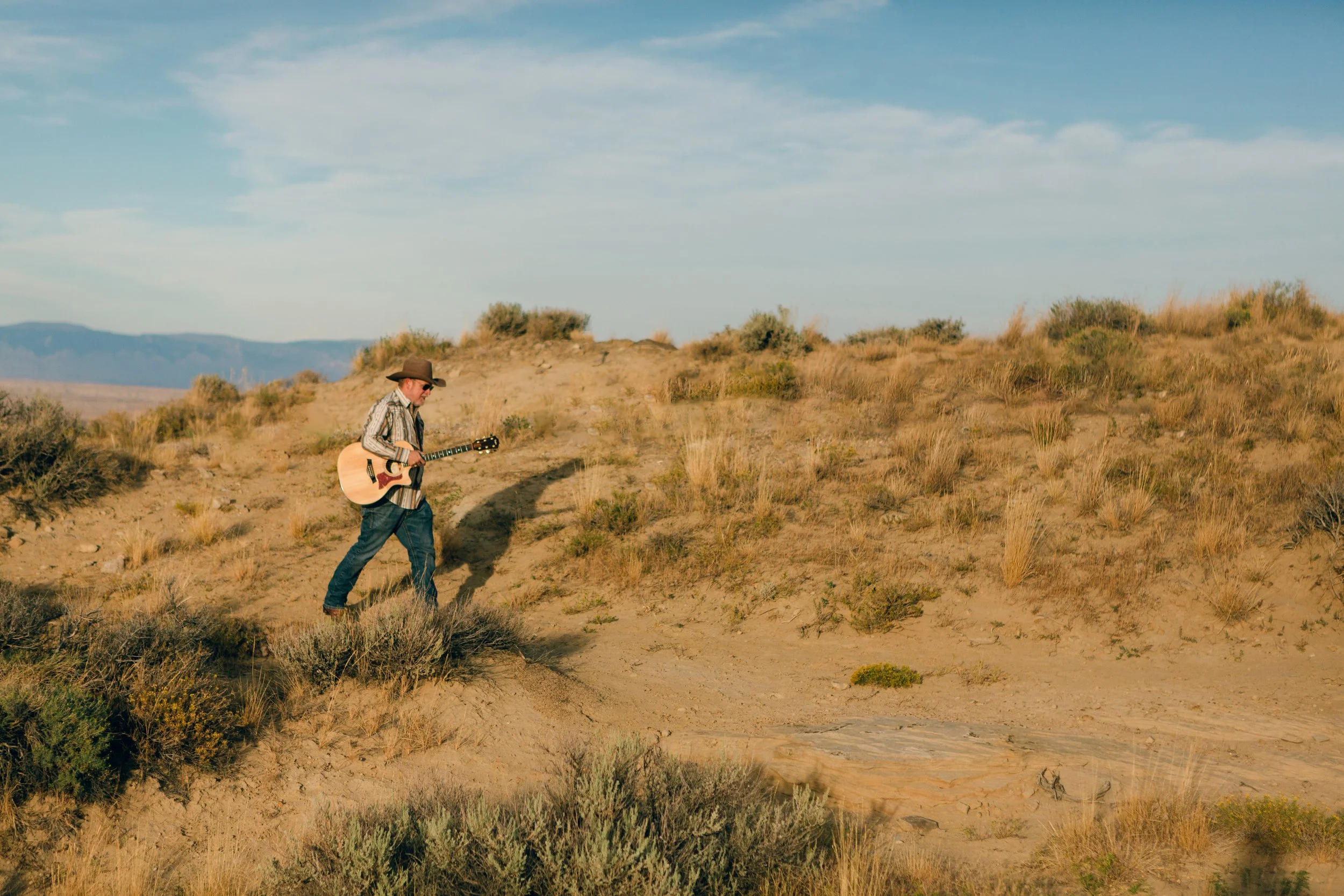 Wyoming musician Aaron Walker walking with his acoustic guitar through the Badlands near Cody, Wyoming.