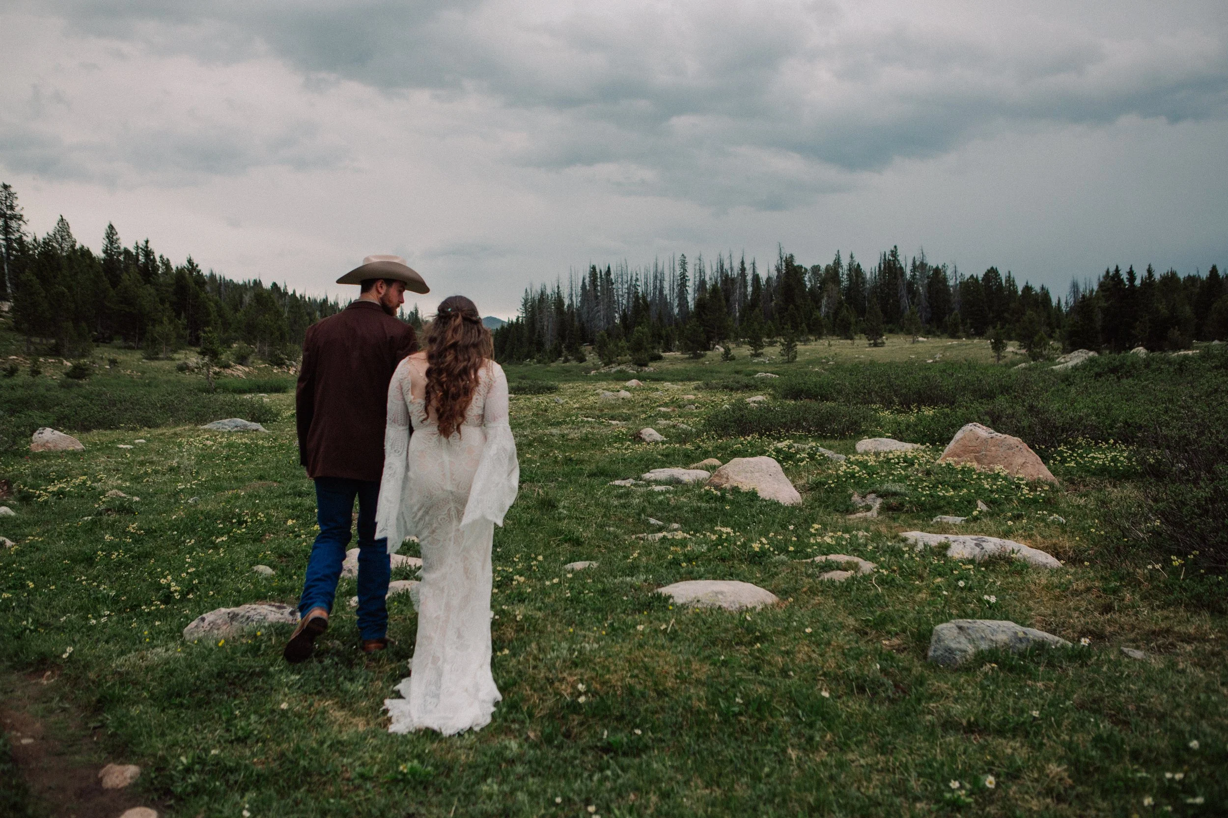 Couple walking through alpine meadow during Wyoming horseback adventure elopement