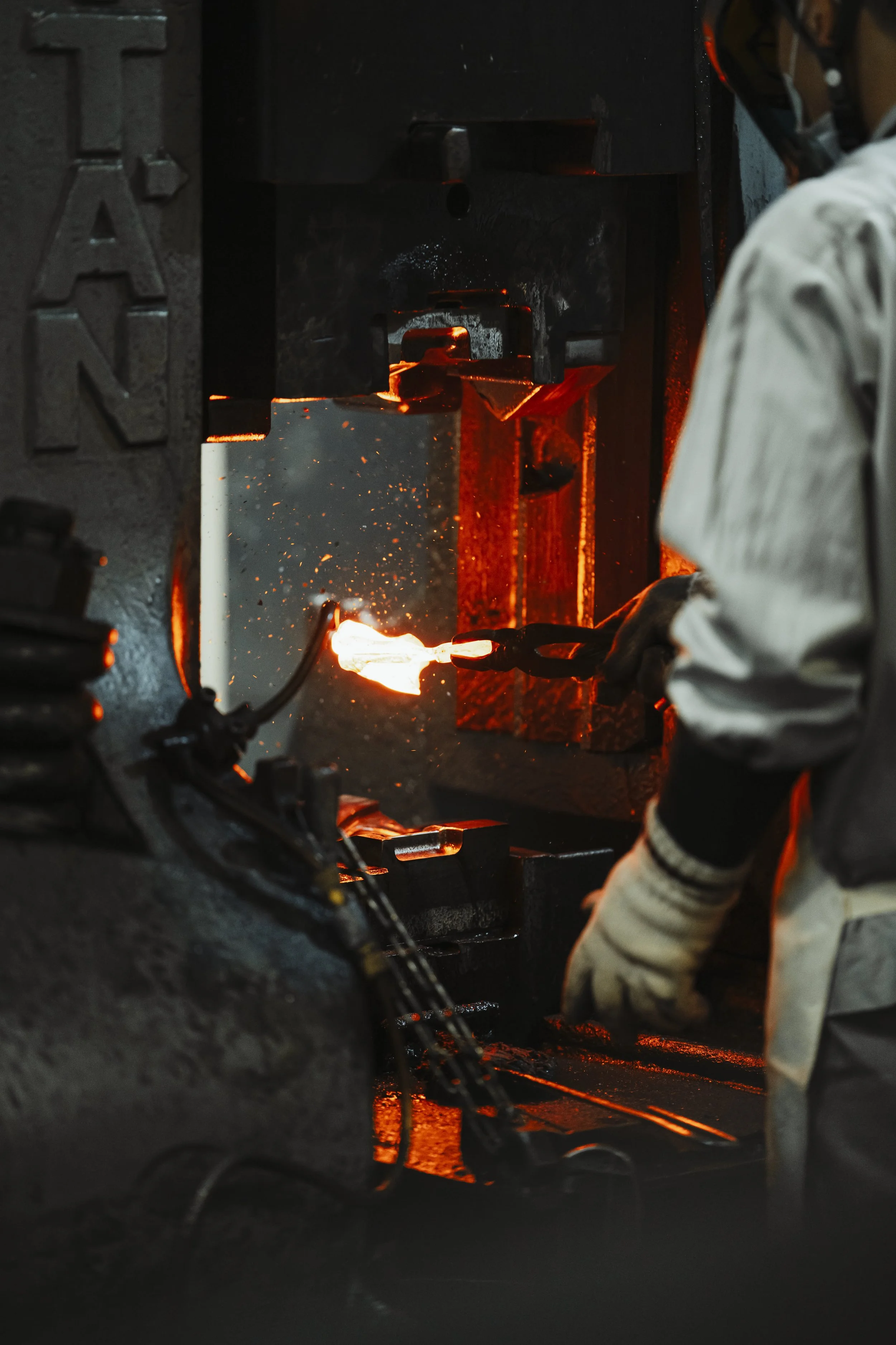 A blacksmith working with fire and metal in a forge, wearing gloves and protective gear.