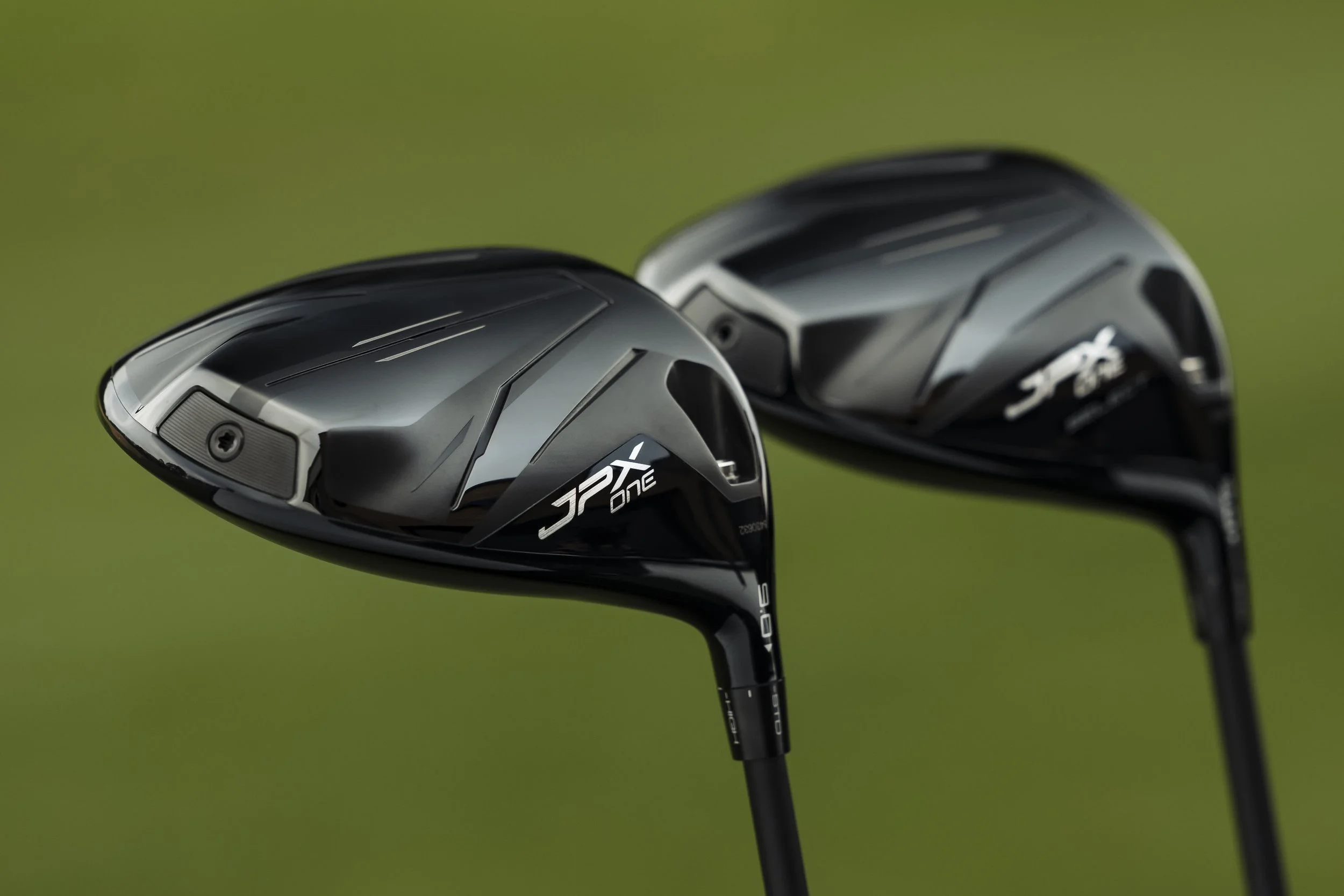 Two black golf clubs with a gray and black design rest on a green background.