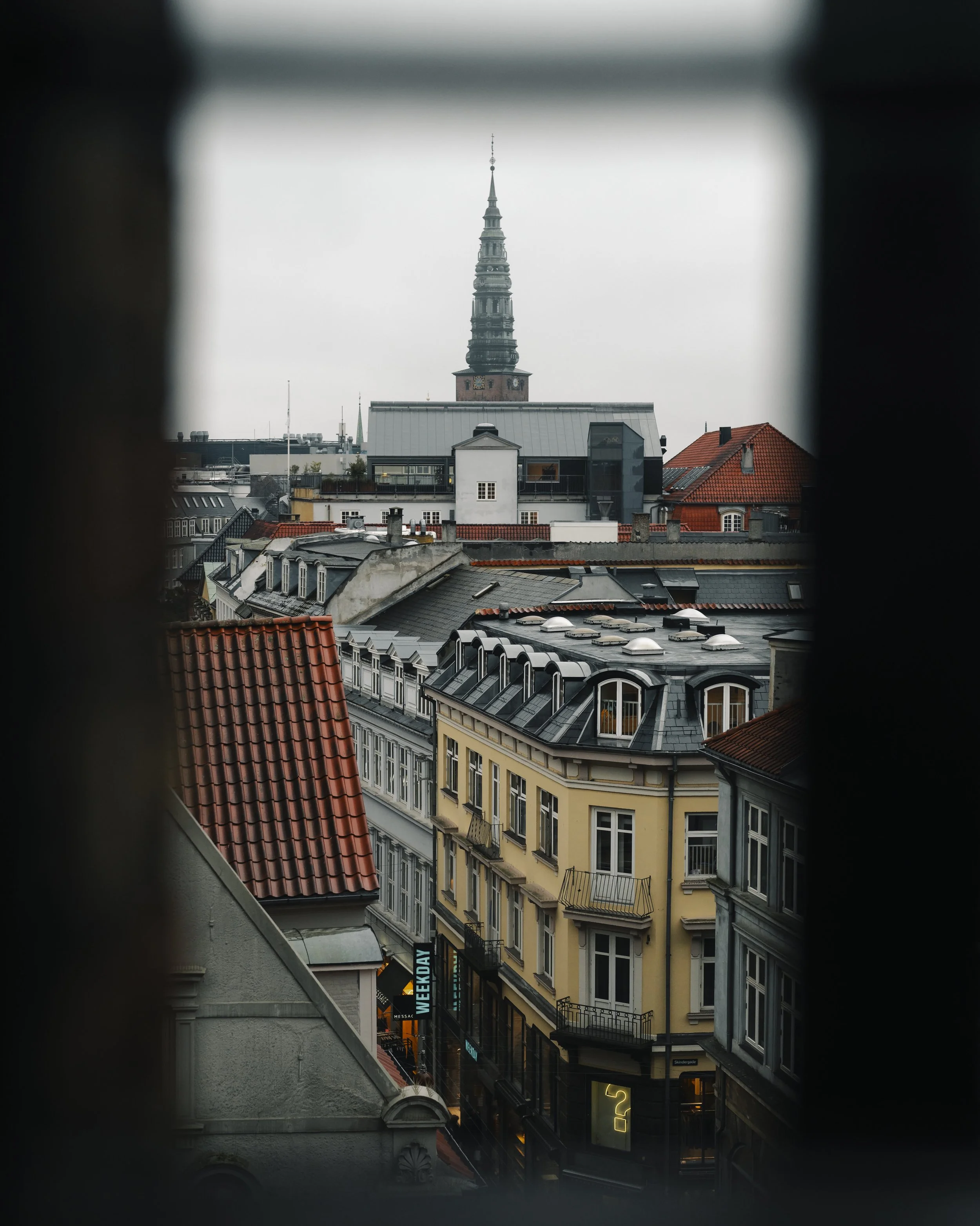 City skyline with historic and modern buildings, view through a window frame, cloudy sky.