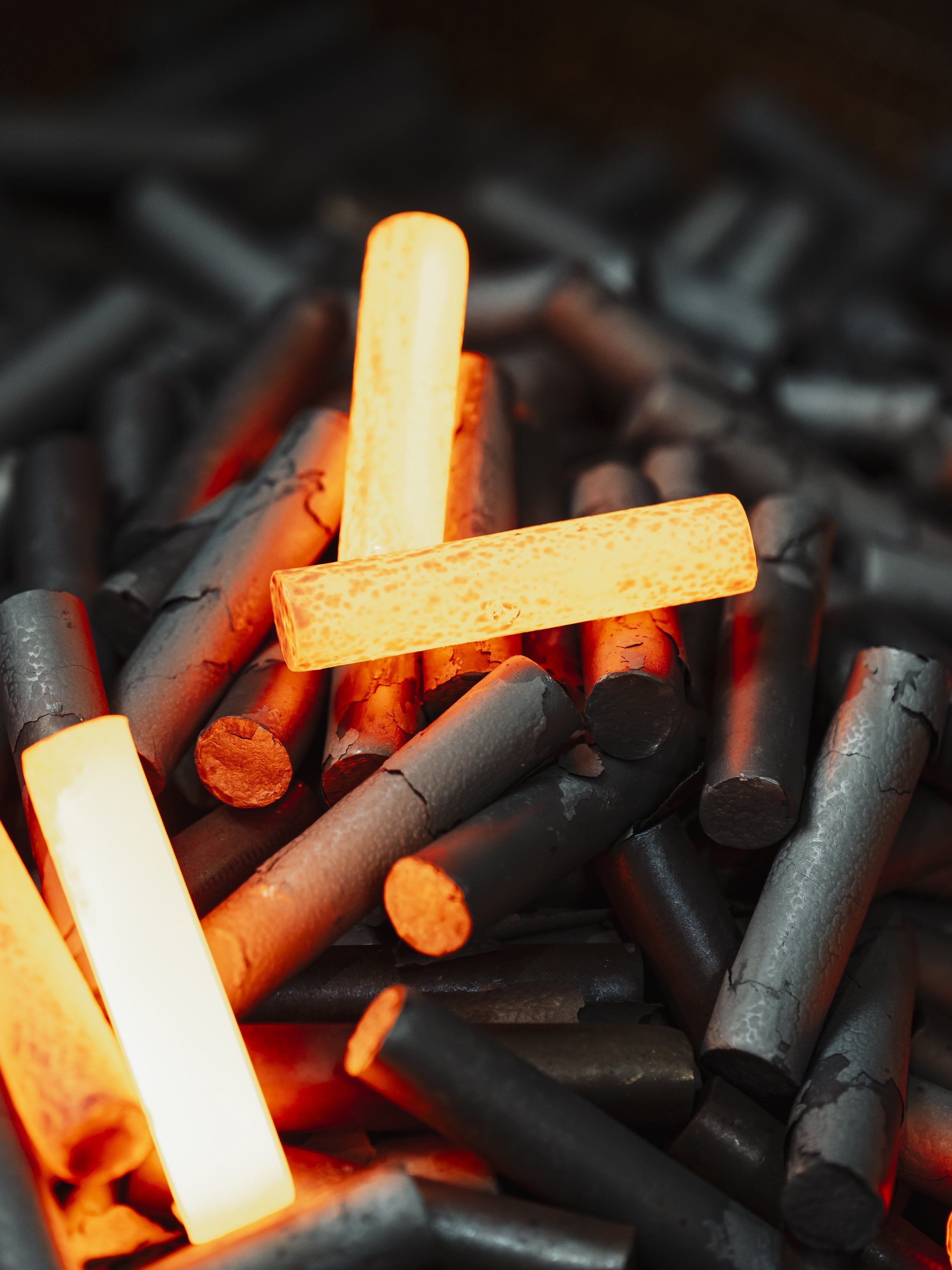 Glowing orange and yellow fire sticks on black charcoal.