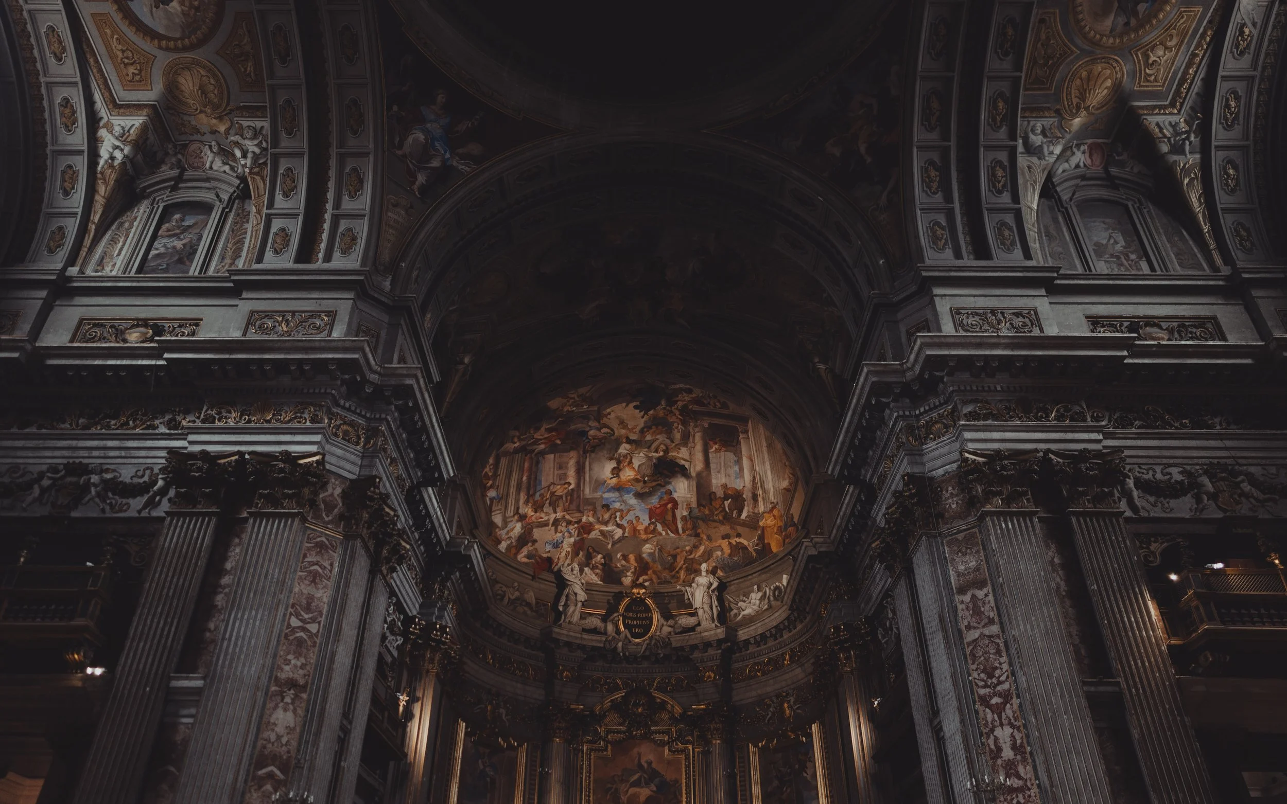 Grand interior of a historic church or cathedral with ornate architecture and a large painted ceiling mural.