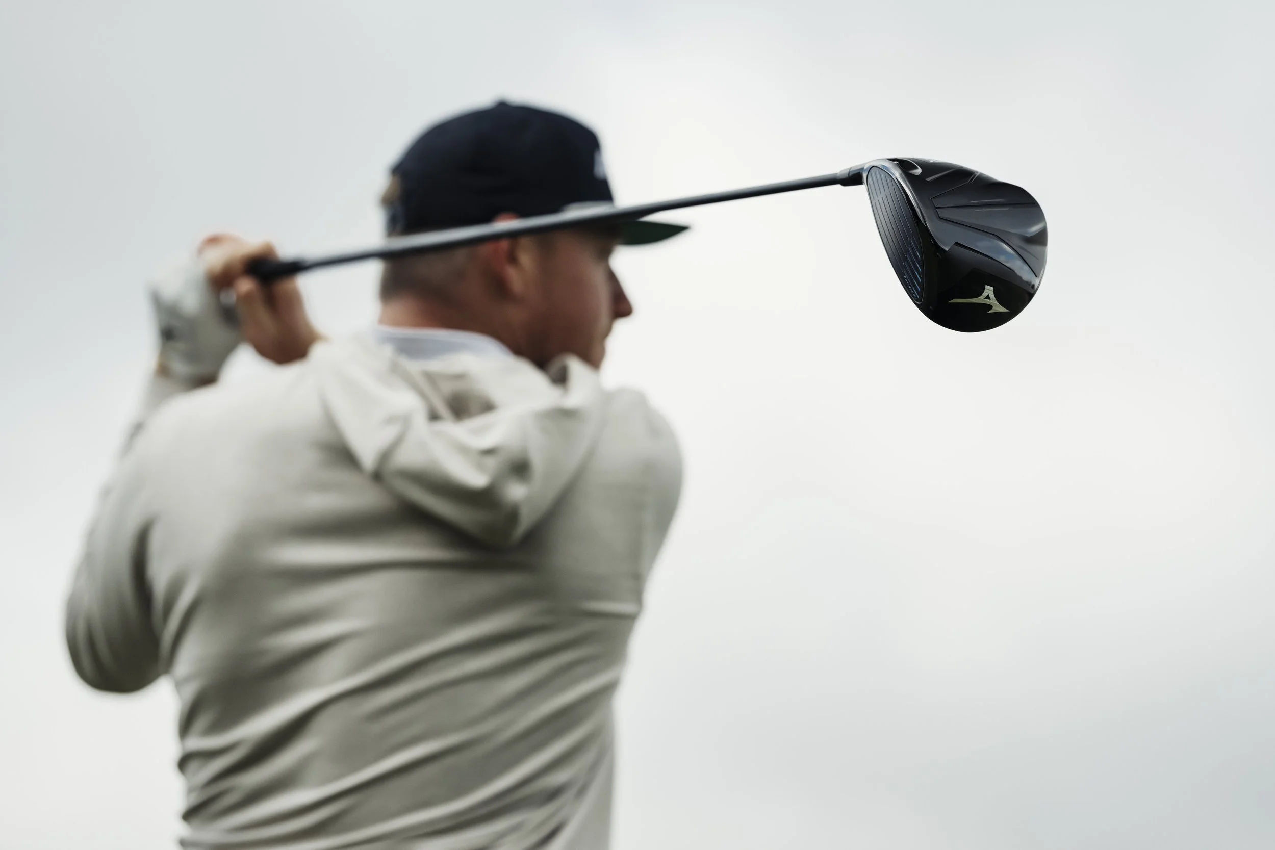 A male golfer swinging a golf club on a cloudy day